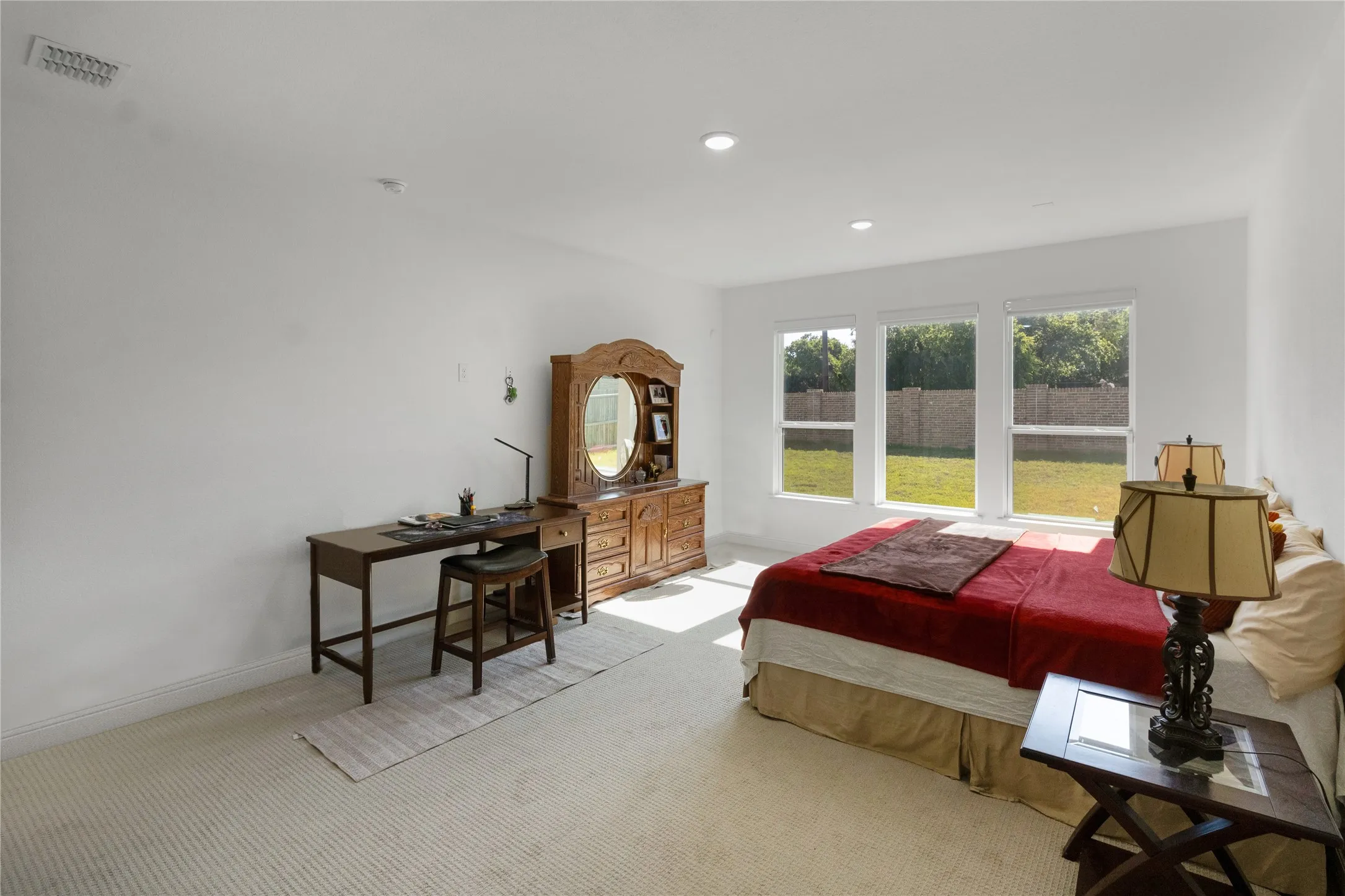 Bright bedroom featuring a trio of windows overlooking the backyard