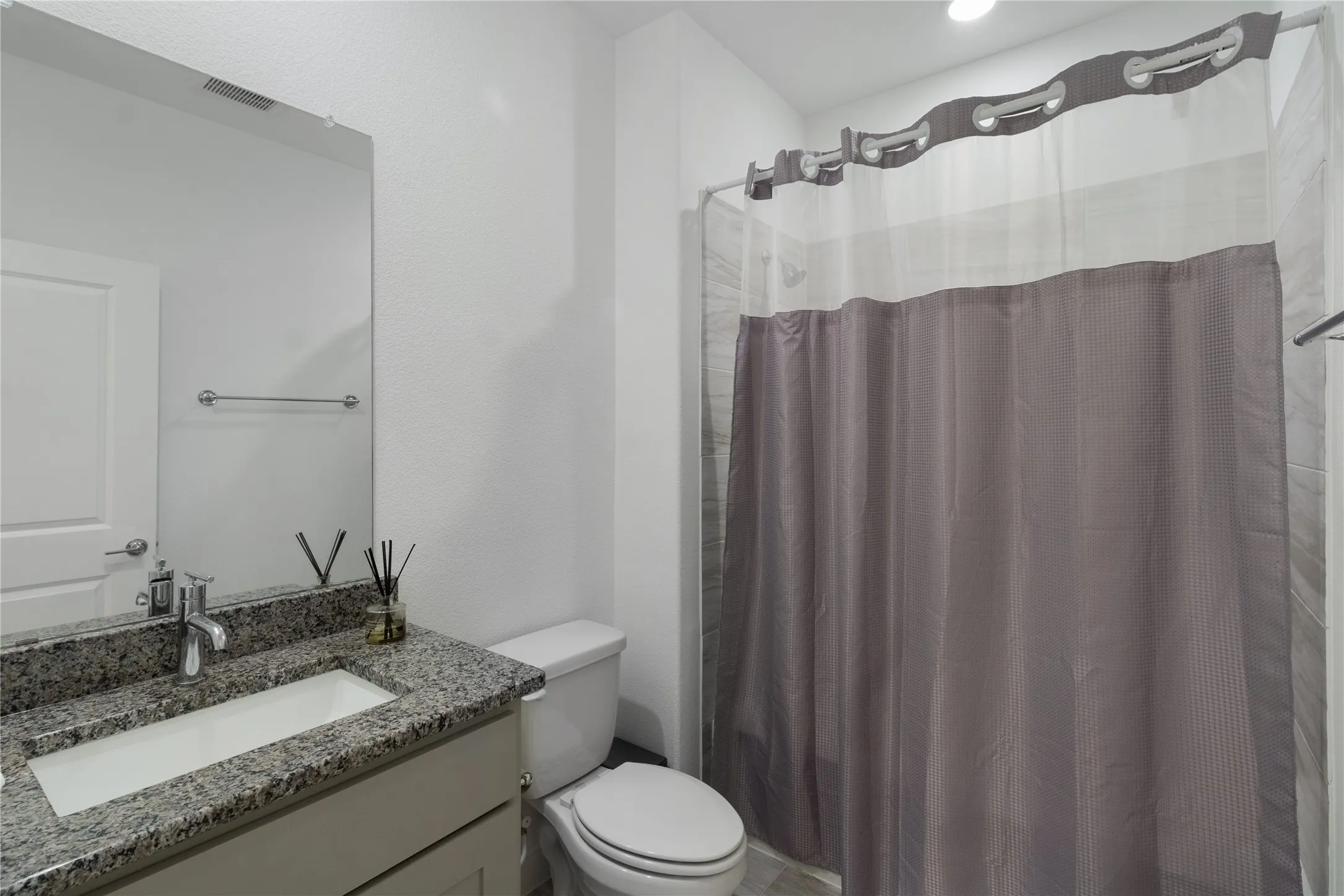 Bathroom featuring a vanity with a granite countertop, integrated rectangular sink, and chrome faucet