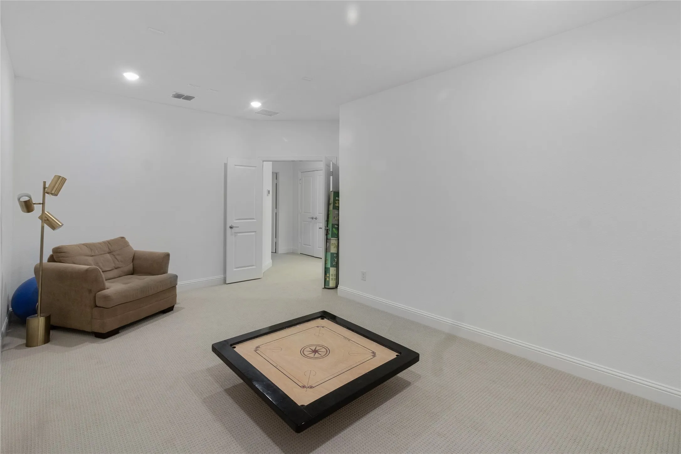 Spacious room featuring light-toned carpeting, recessed lighting, and white baseboards