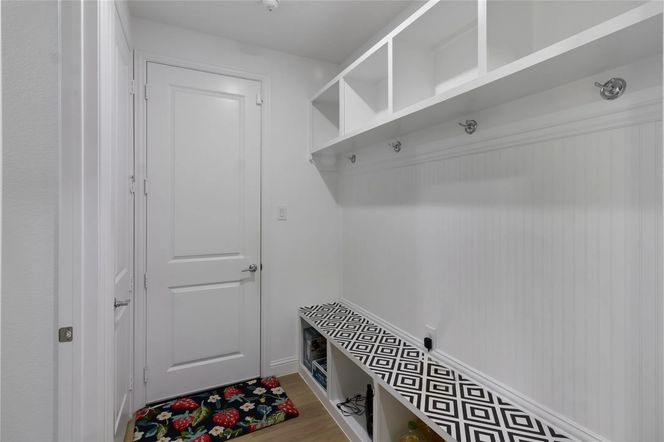 Entryway mudroom featuring built-in storage bench, open shelving, and coat hooks