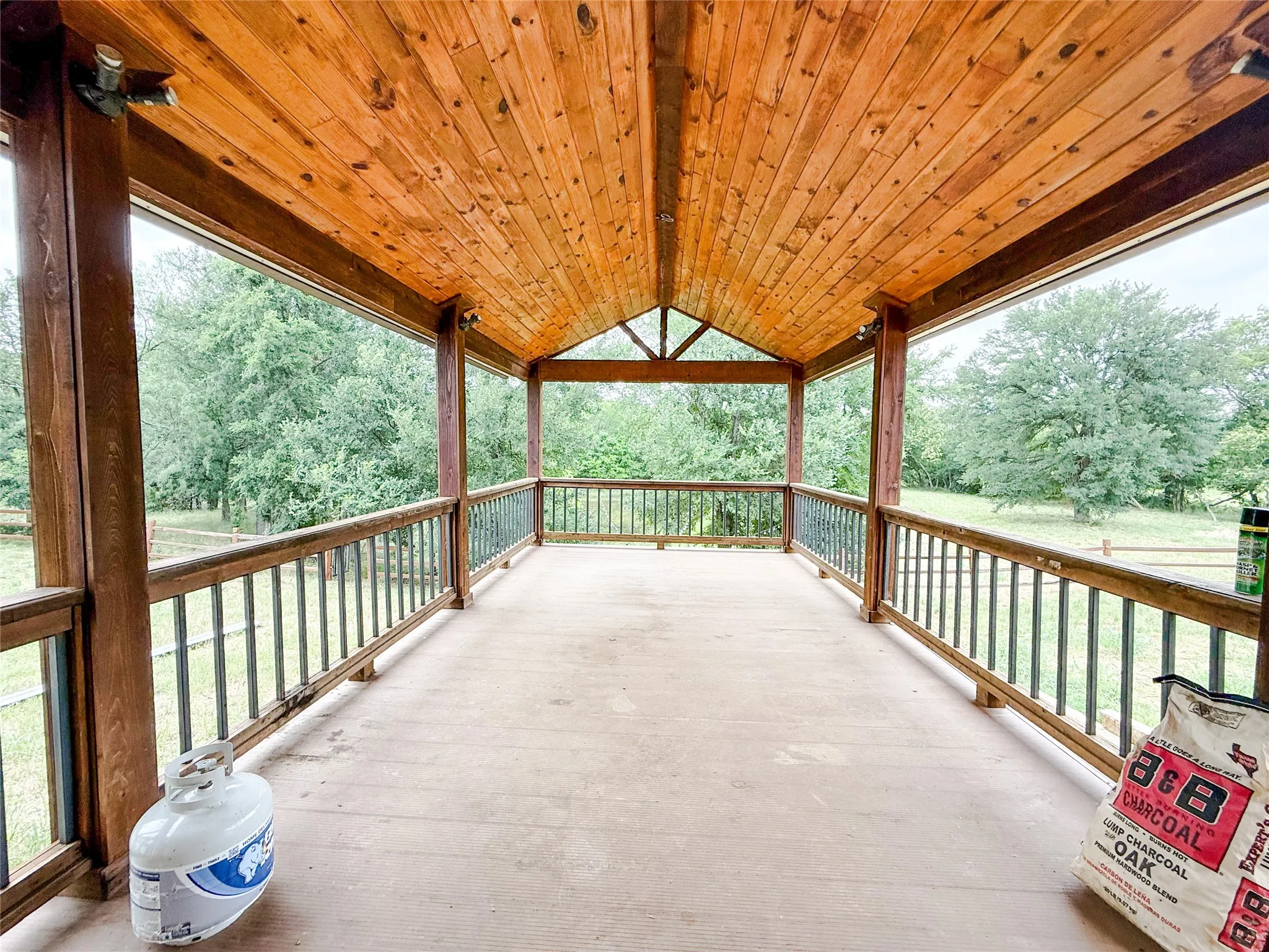 Expansive covered porch featuring a natural wood ceiling, exposed beams, and a concrete​​‌​​​​‌​​‌‌​‌‌​​​‌‌​‌​‌​‌​​​‌​​ floor