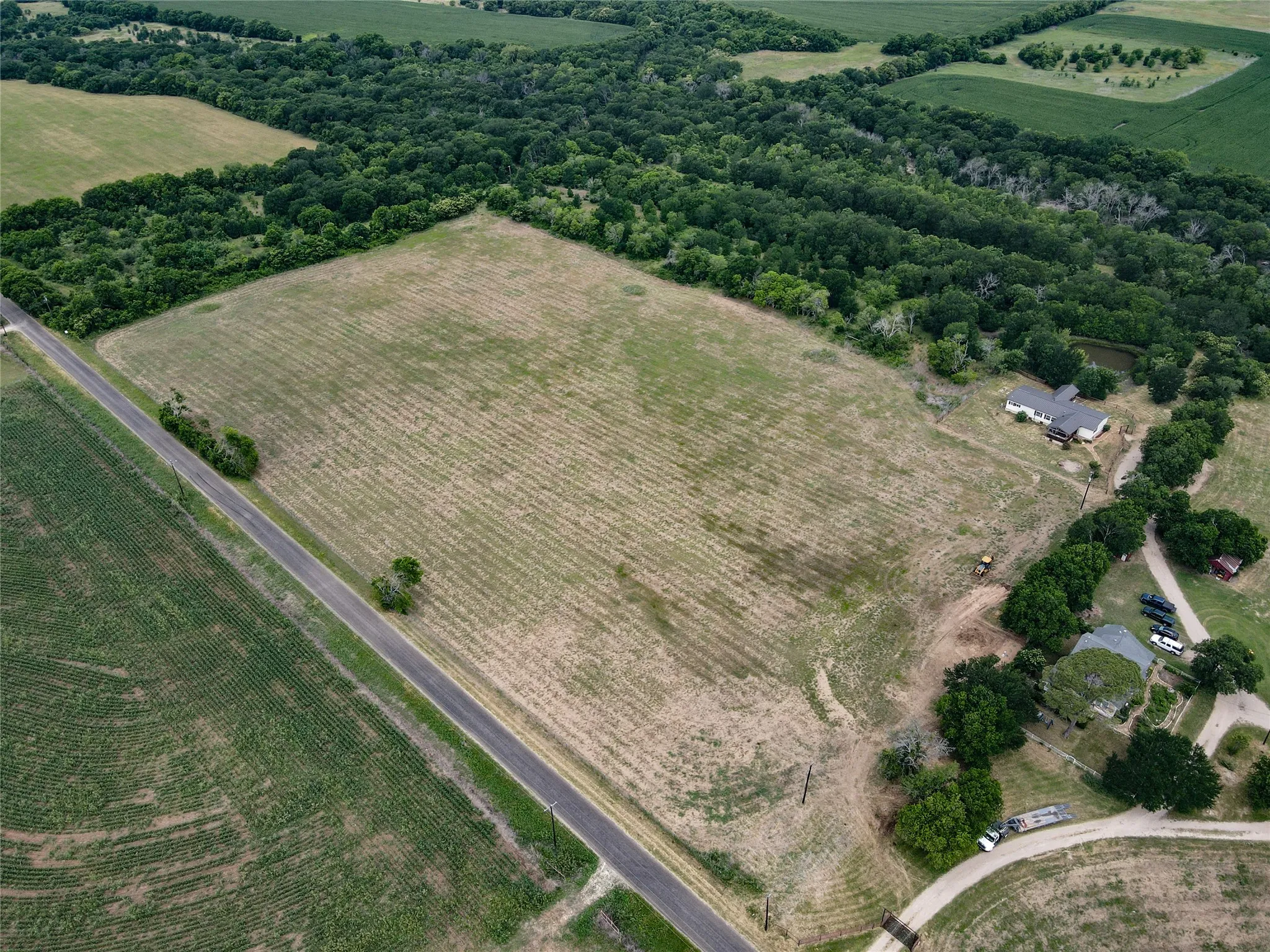 Expansive land parcel featuring cultivated fields bordering a paved roadway