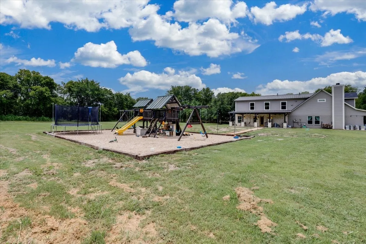 Expansive rear grounds featuring a dedicated play area with a wooden playset and a large trampoline