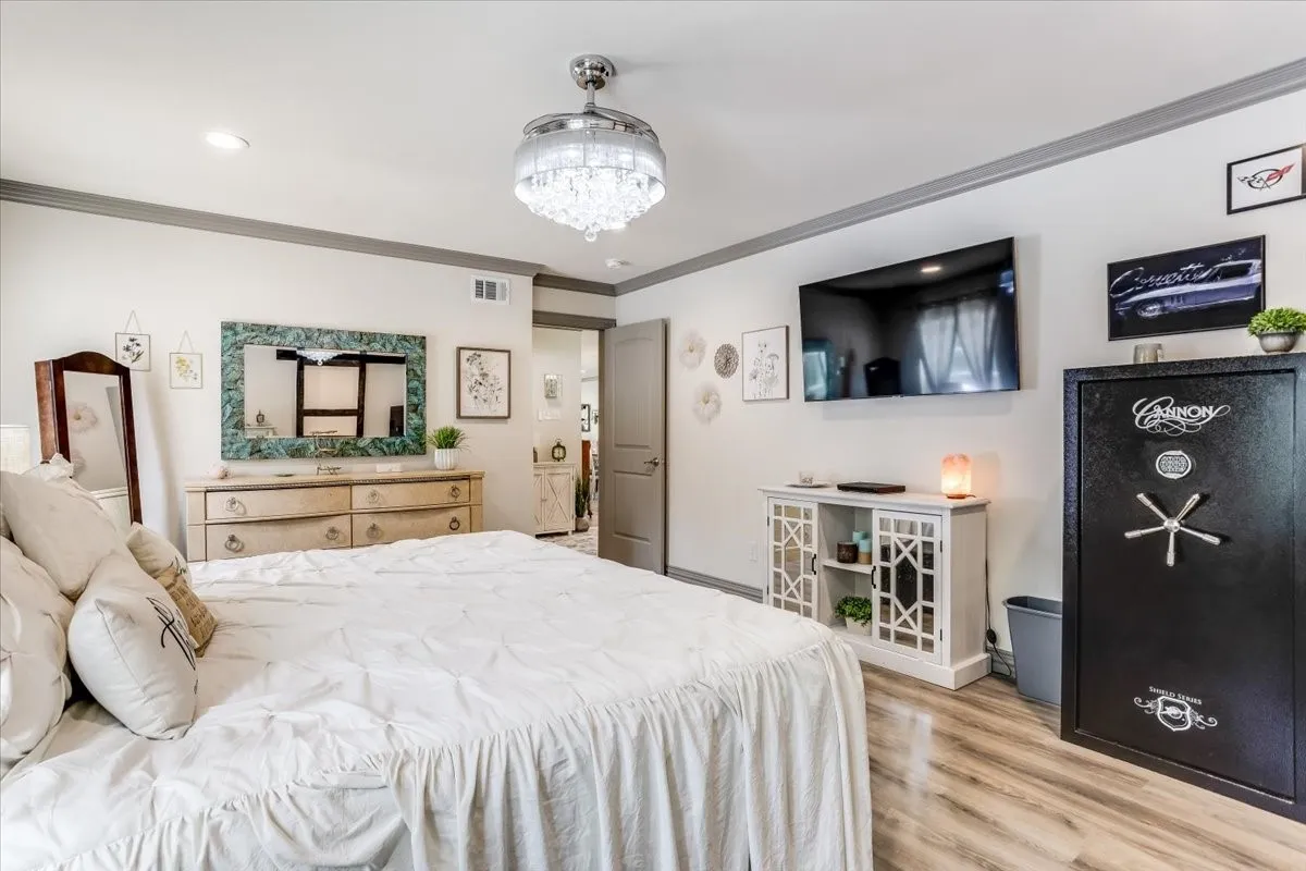 Spacious room featuring wood-finish flooring, a contemporary crystal chandelier, recessed lighting, and a neutral color palette with contrasting trim