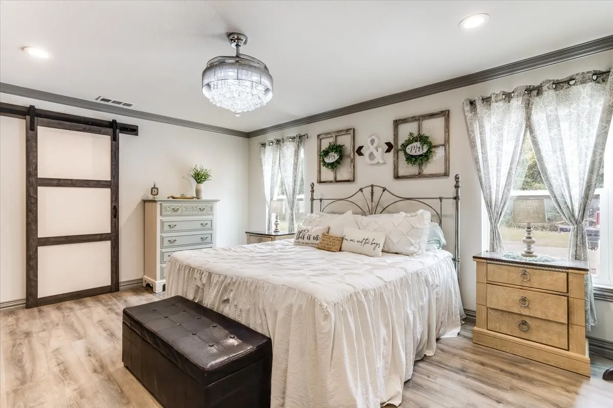 Spacious room featuring wood-finish flooring, a contemporary ceiling fan with integrated lighting, recessed lighting, and a sliding barn door with frosted glass panels