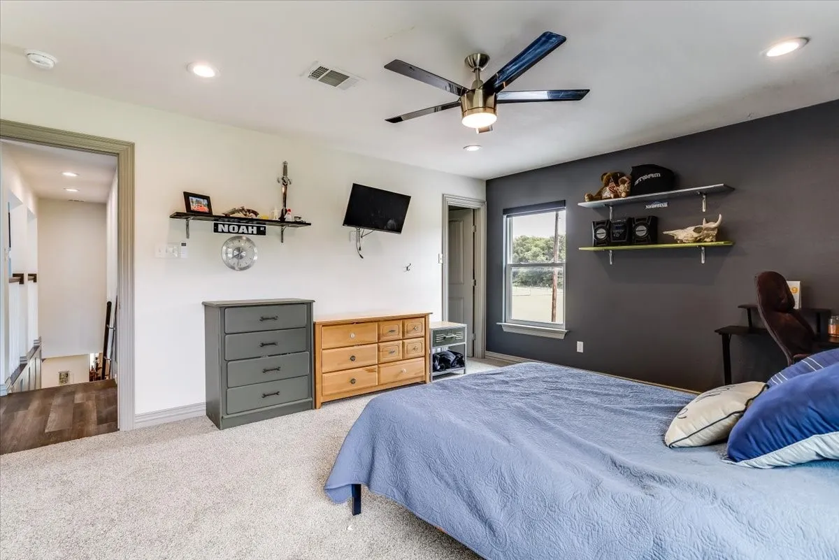 Carpeted room featuring a ceiling fan with integrated lighting, recessed lighting, and a window with a roller shade