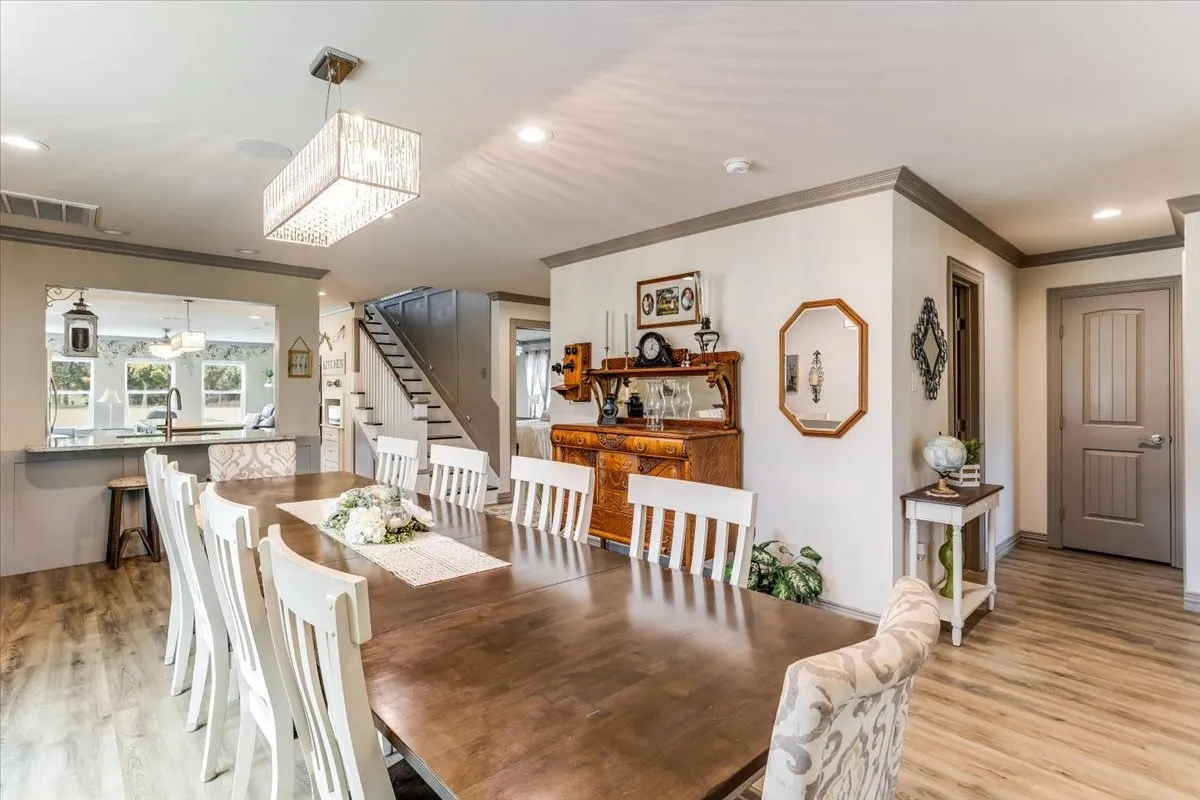 Spacious dining area featuring wood-finish flooring, a contemporary rectangular light fixture, and a pass-through window to the kitchen