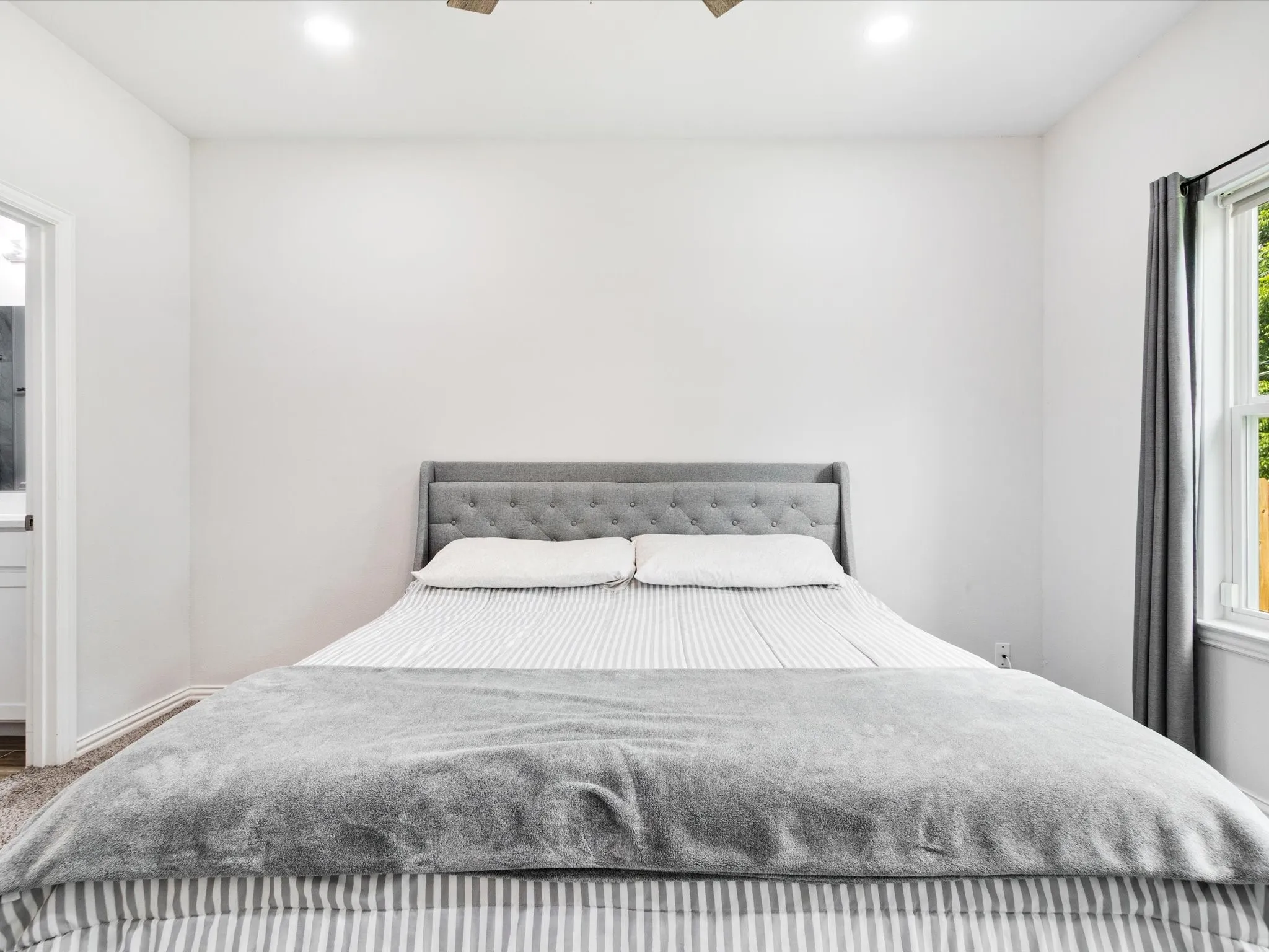 Bedroom featuring plush carpeting, a large window with natural light, recessed ceiling lighting, and a ceiling fan