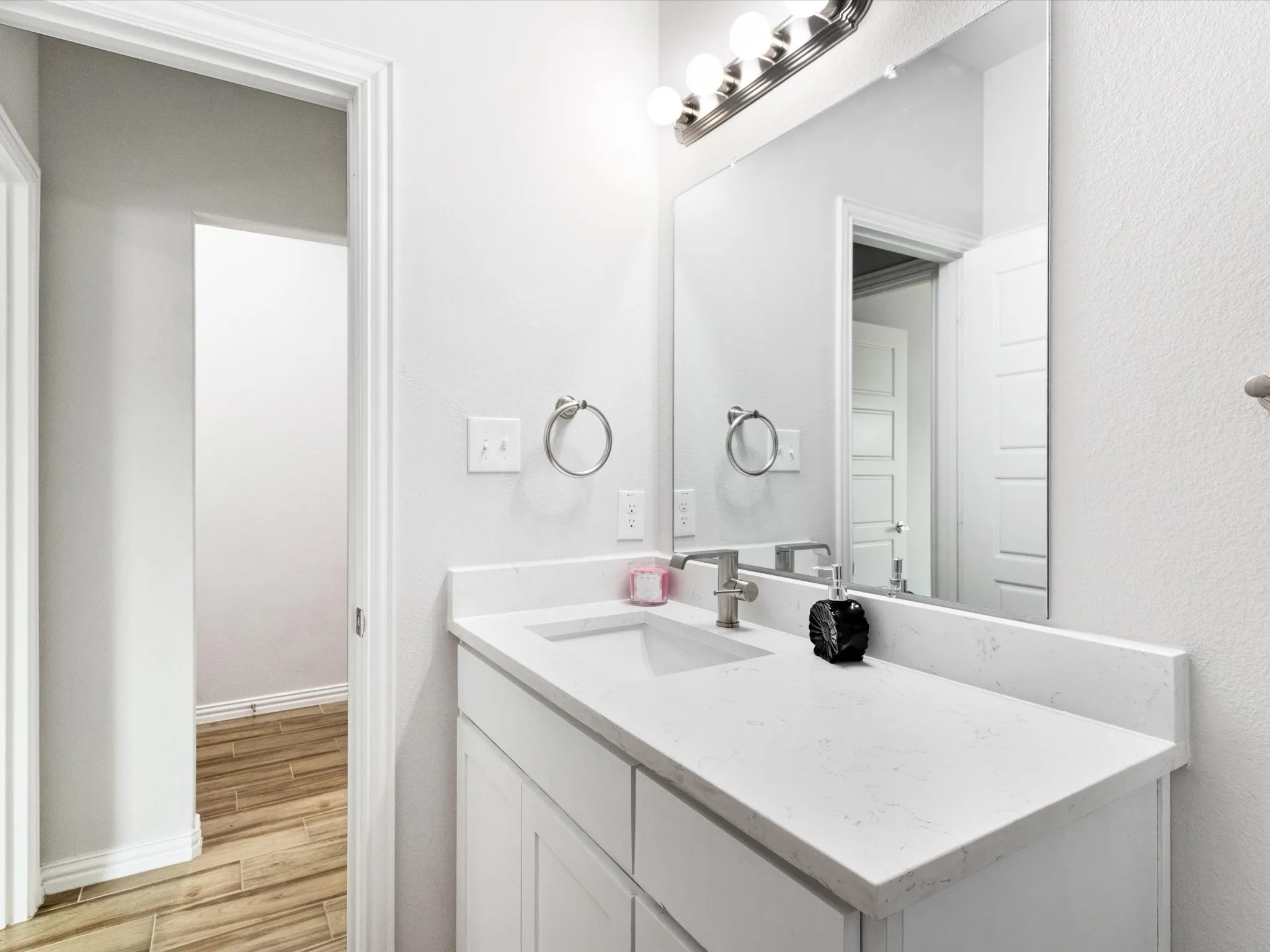 Bathroom featuring a single vanity with white cabinetry, a light-colored countertop, and an integrated sink with a brushed nickel faucet