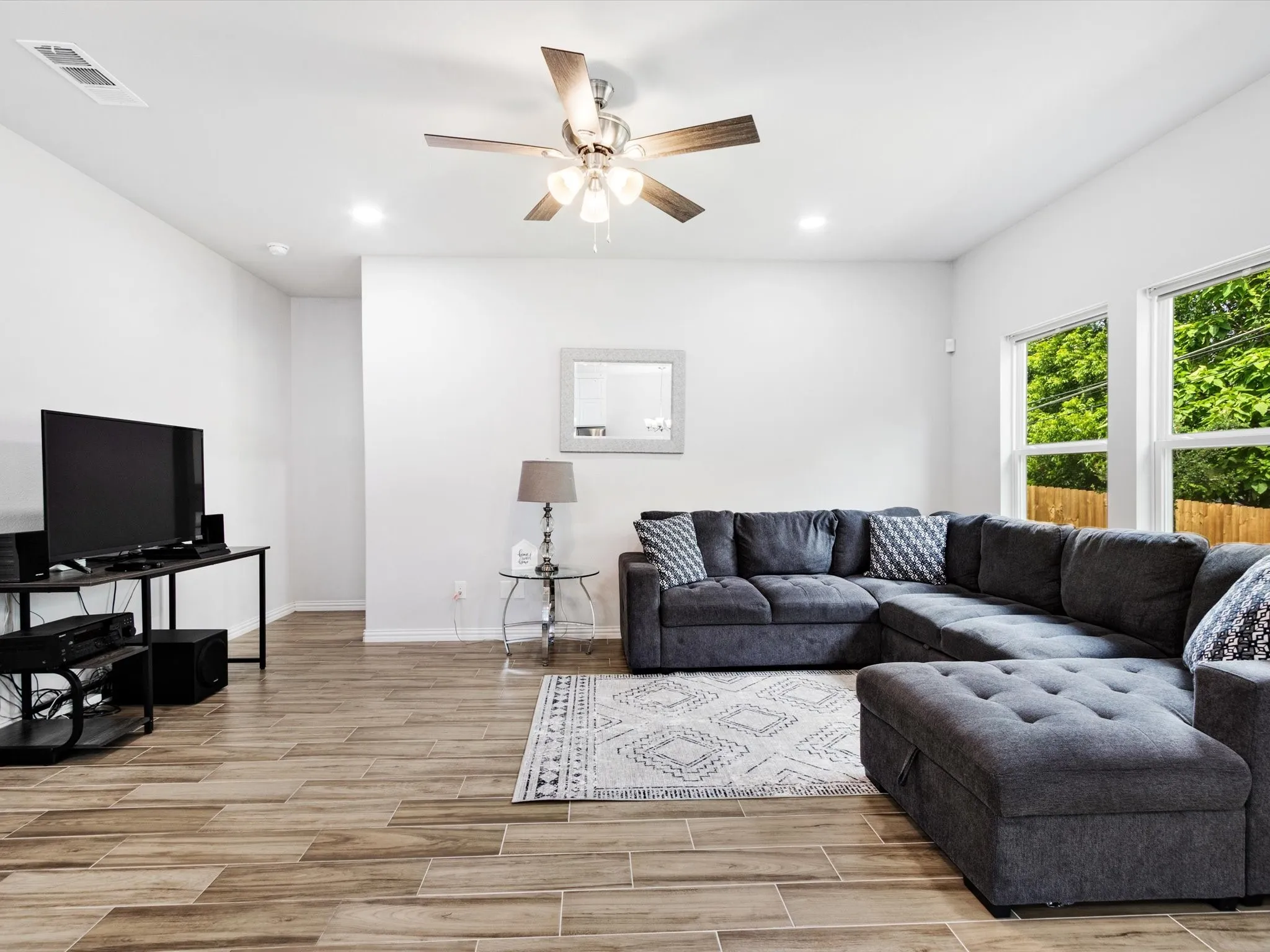 Spacious living area featuring wood-finish flooring and a contemporary ceiling fan with lighting