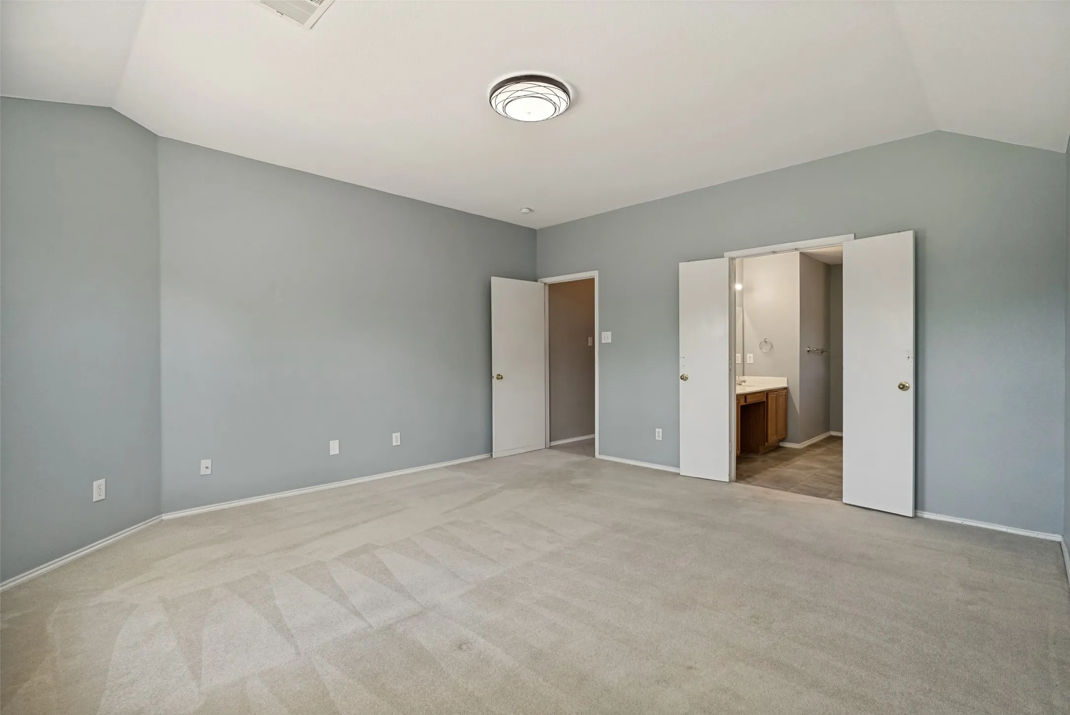 Spacious room featuring vaulted ceilings, light gray wall paint, and light-colored carpeting