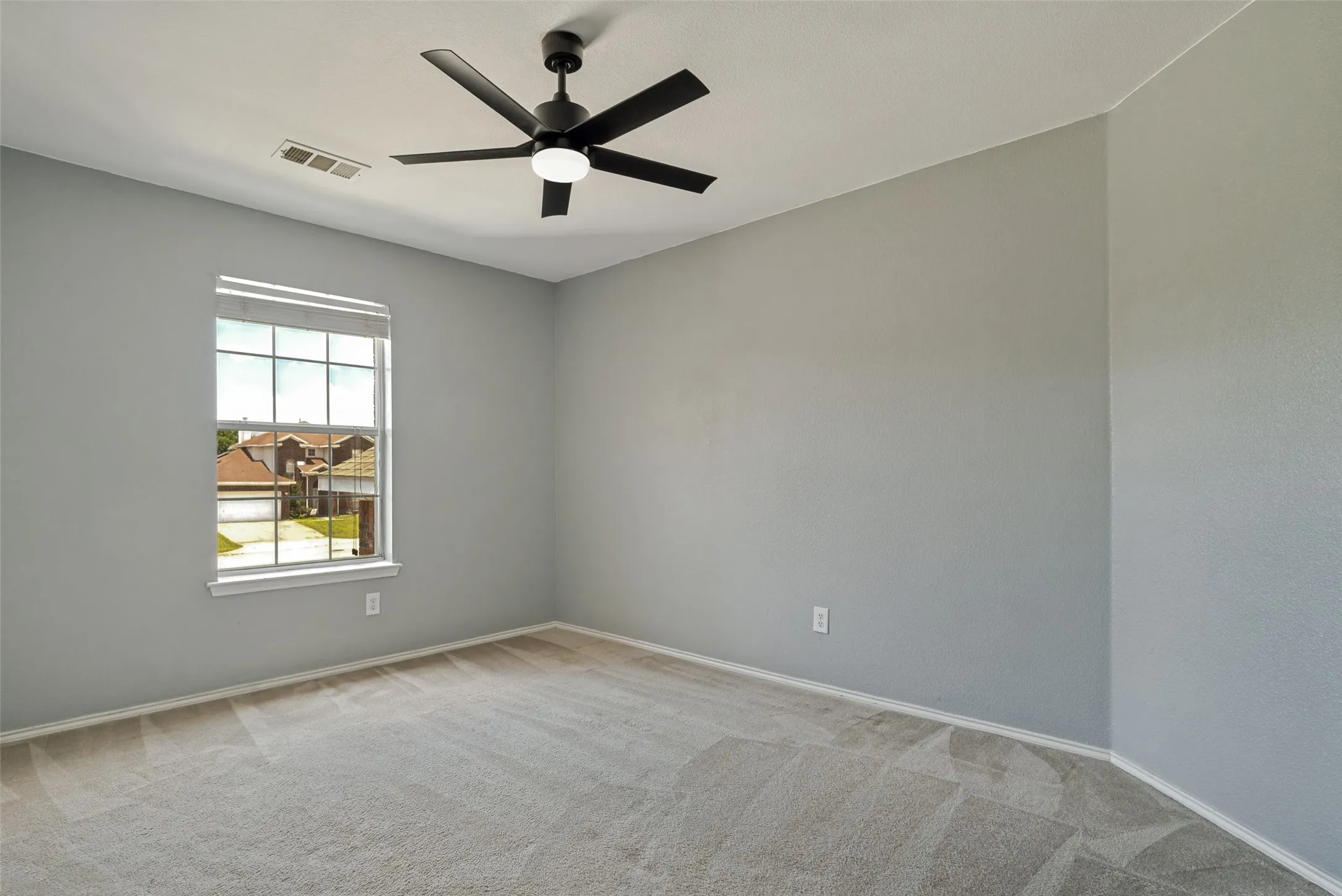 Carpeted room with a ceiling fan and a window featuring white trim