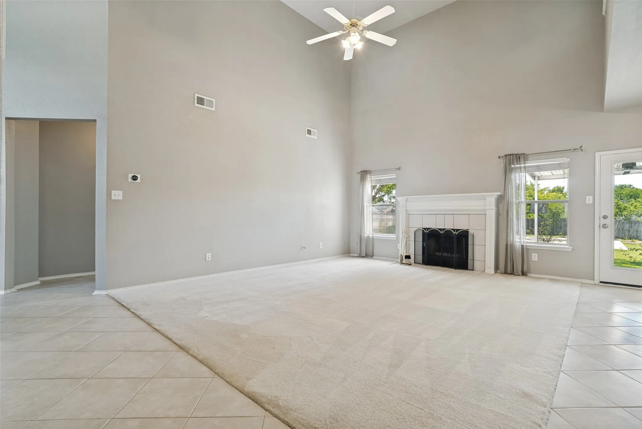Spacious living area featuring a vaulted ceiling and a ceiling fan