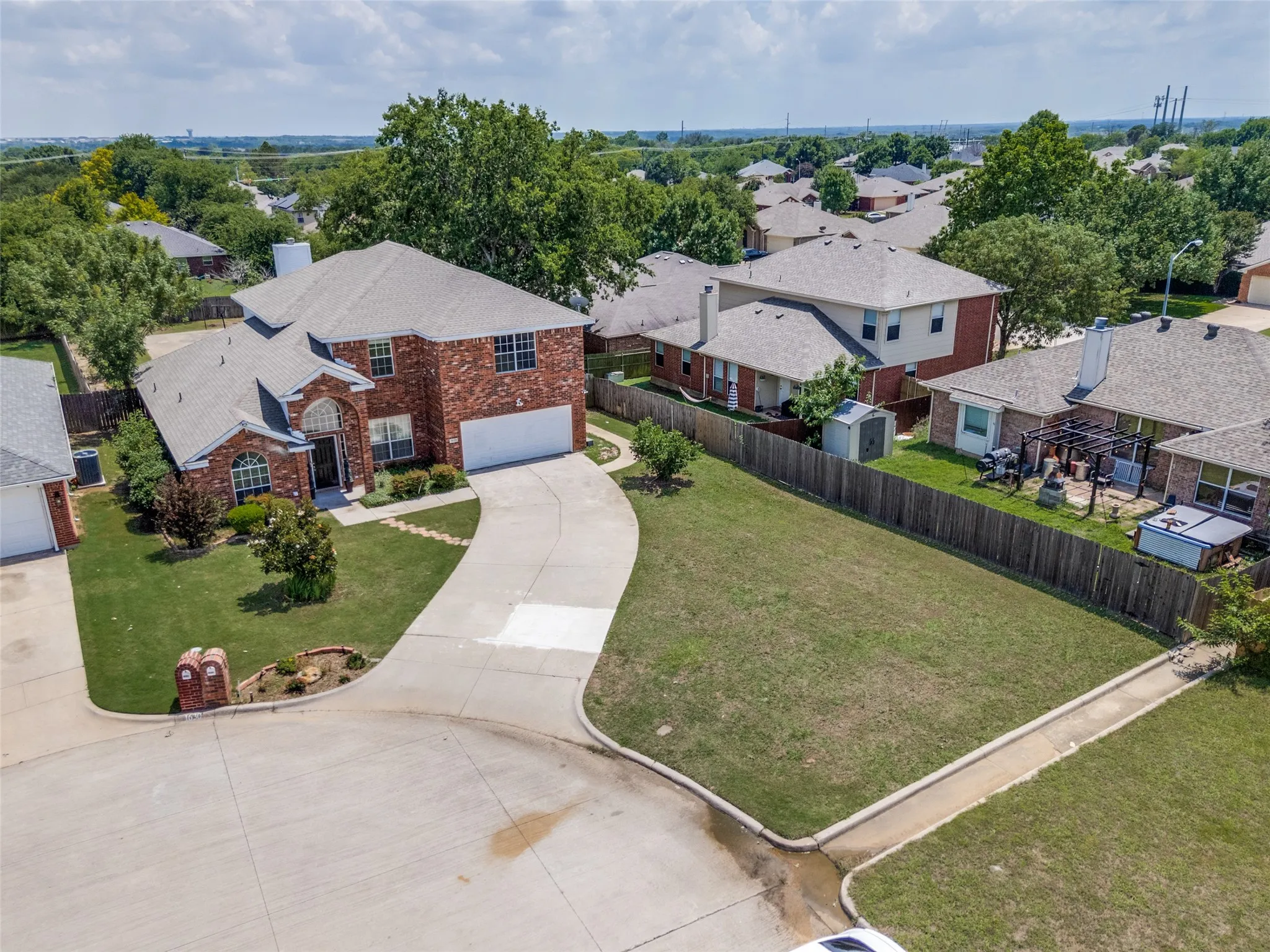 Brick exterior featuring a two-car garage, established front yard landscaping, and a concrete driveway