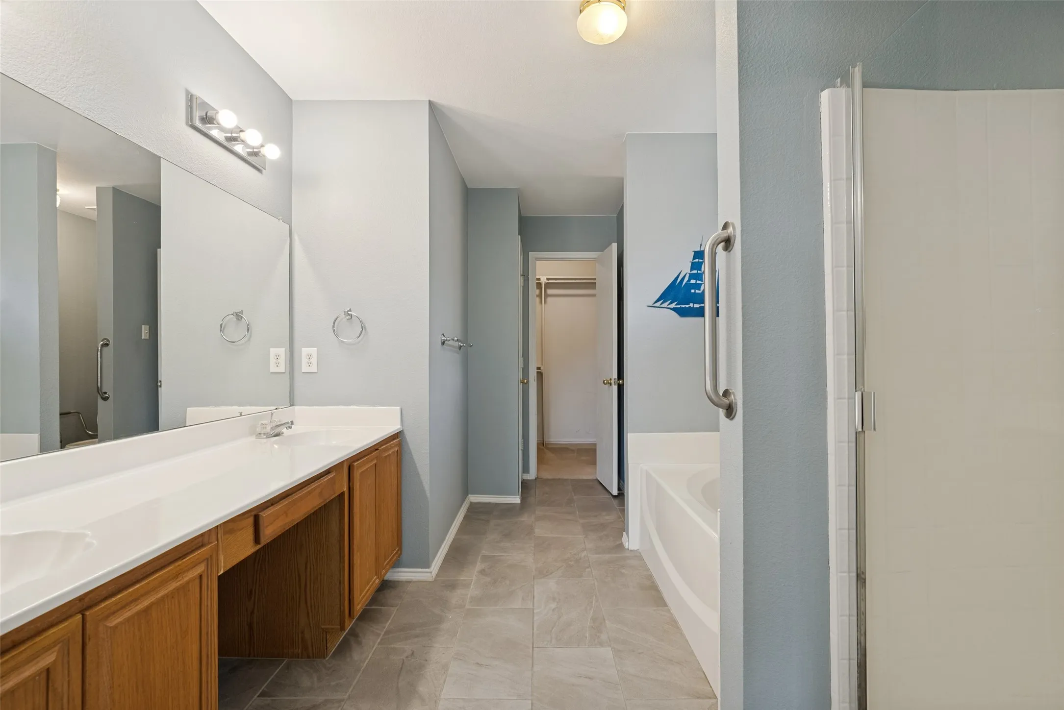 Expansive vanity with dual sinks, white countertop, and light wood-finish cabinetry
