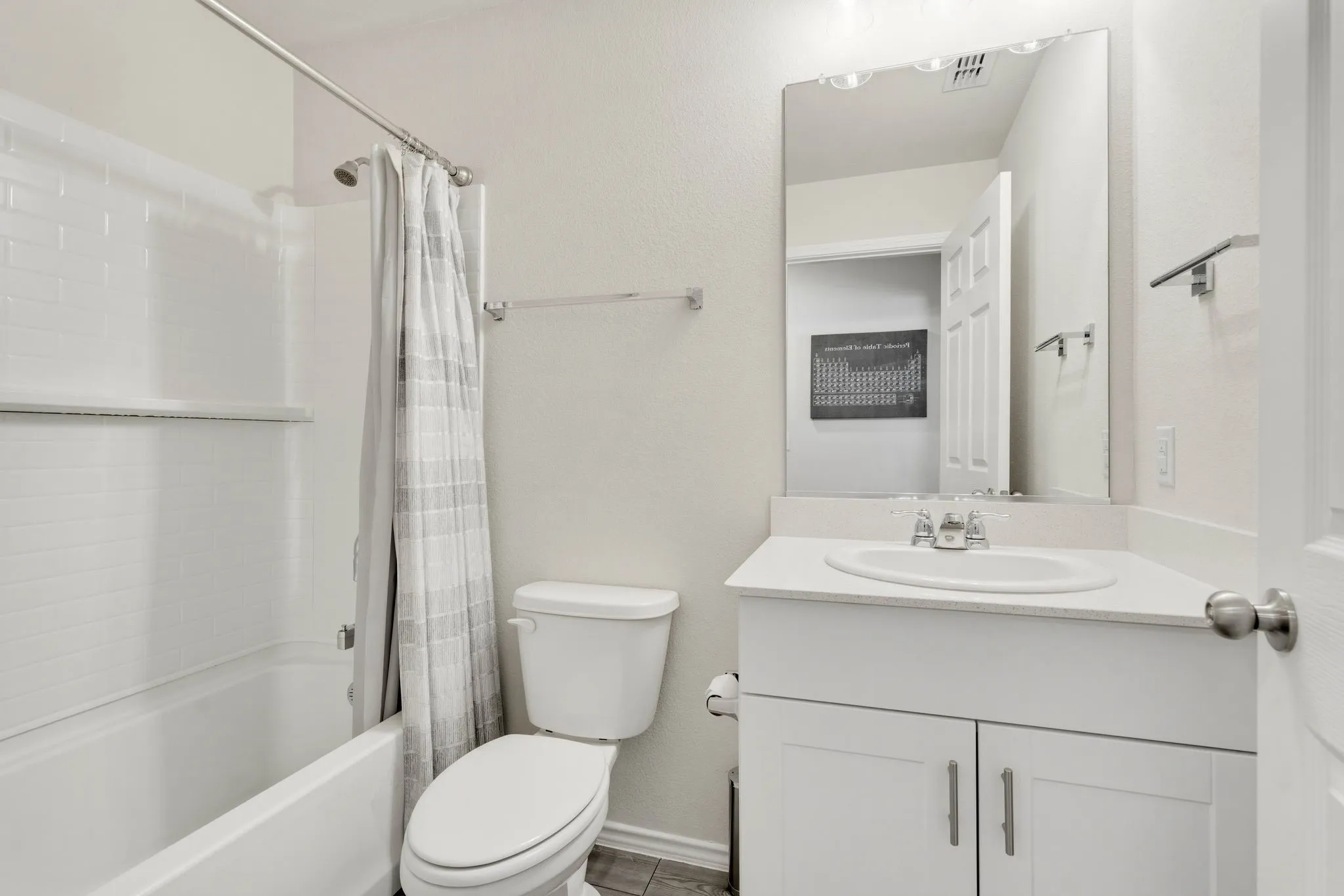 Bathroom featuring a white bathtub with subway tile surround, a single vanity with a white countertop and integrated sink, and a large wall mirror,