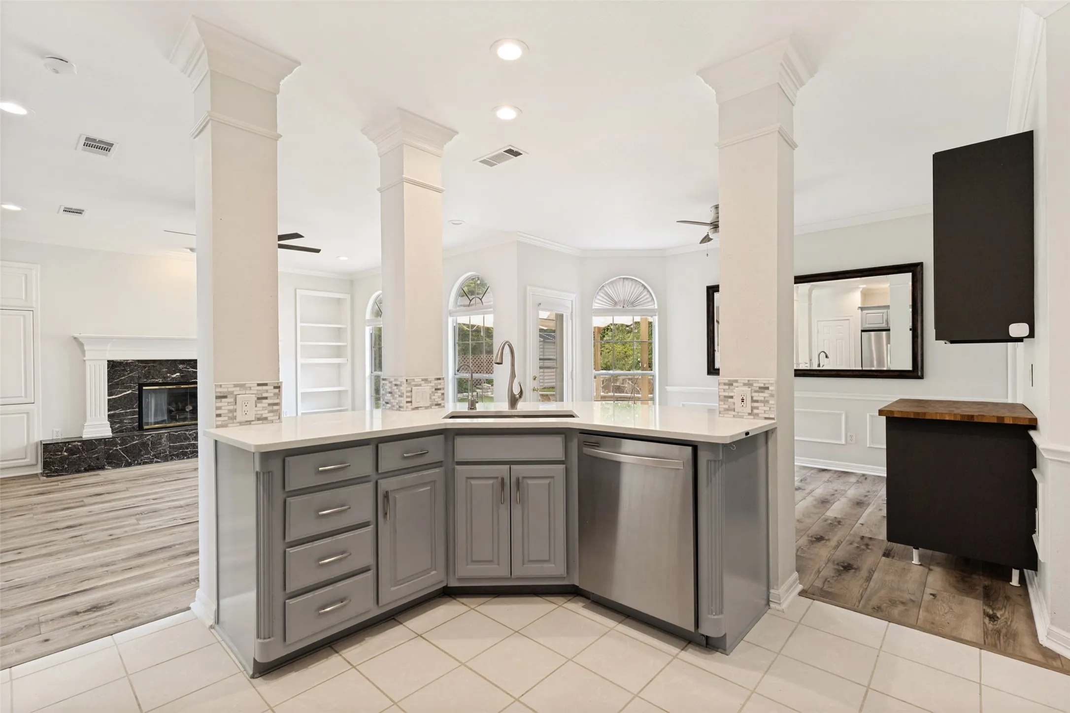 Kitchen featuring grey cabinetry, white countertops, tile flooring, and a stainless steel dishwasher