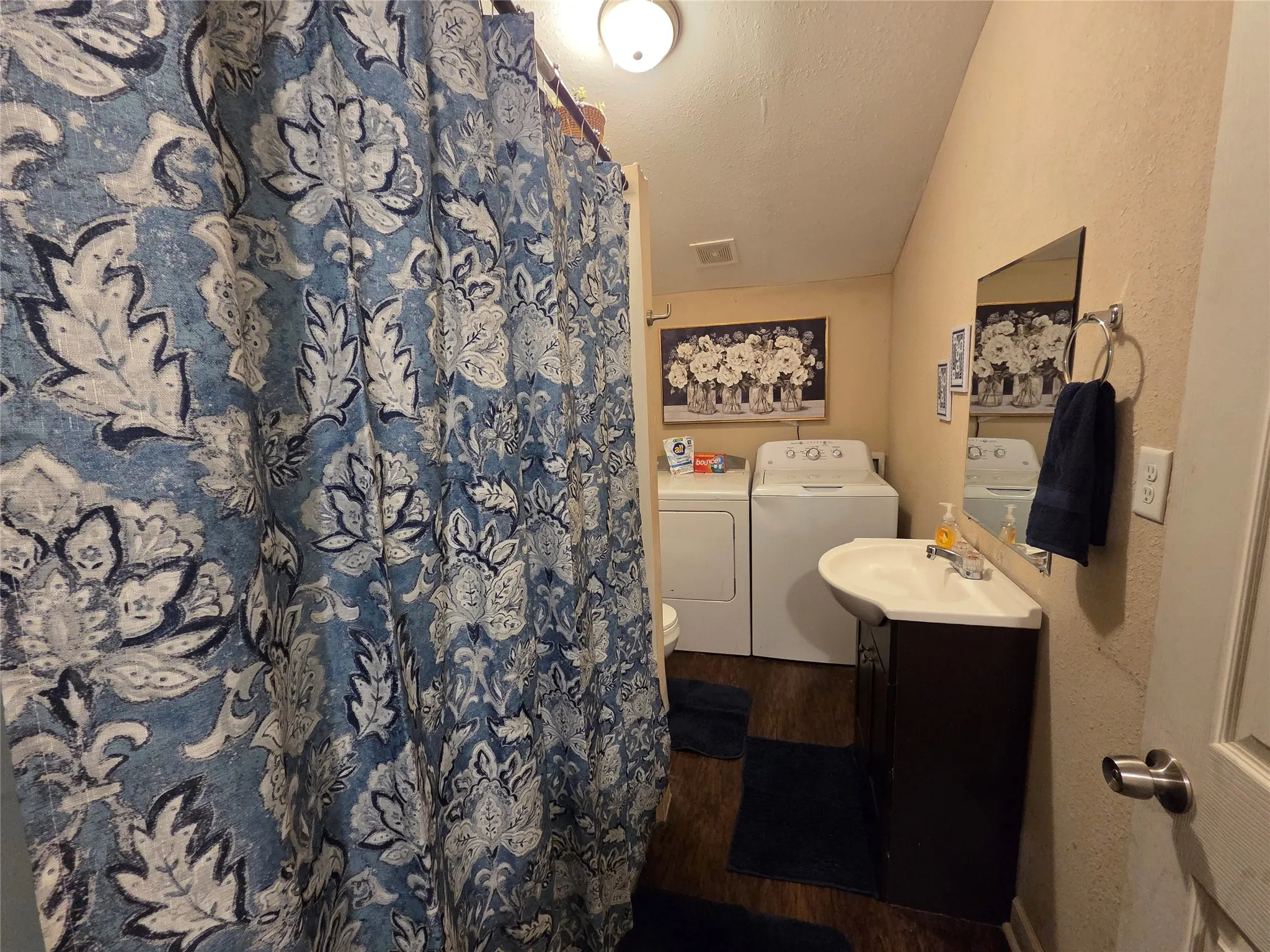 Bathroom with tub/shower combo, vanity, commode, and full size washer and dryer