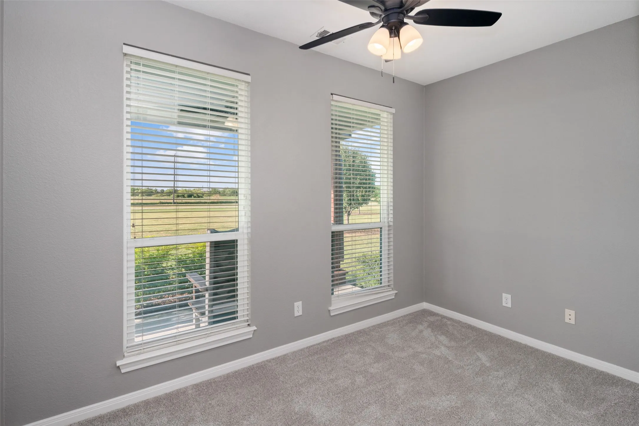 Bedroom featuring two windows with horizontal blinds, gray wall paint, and gray carpet flooring