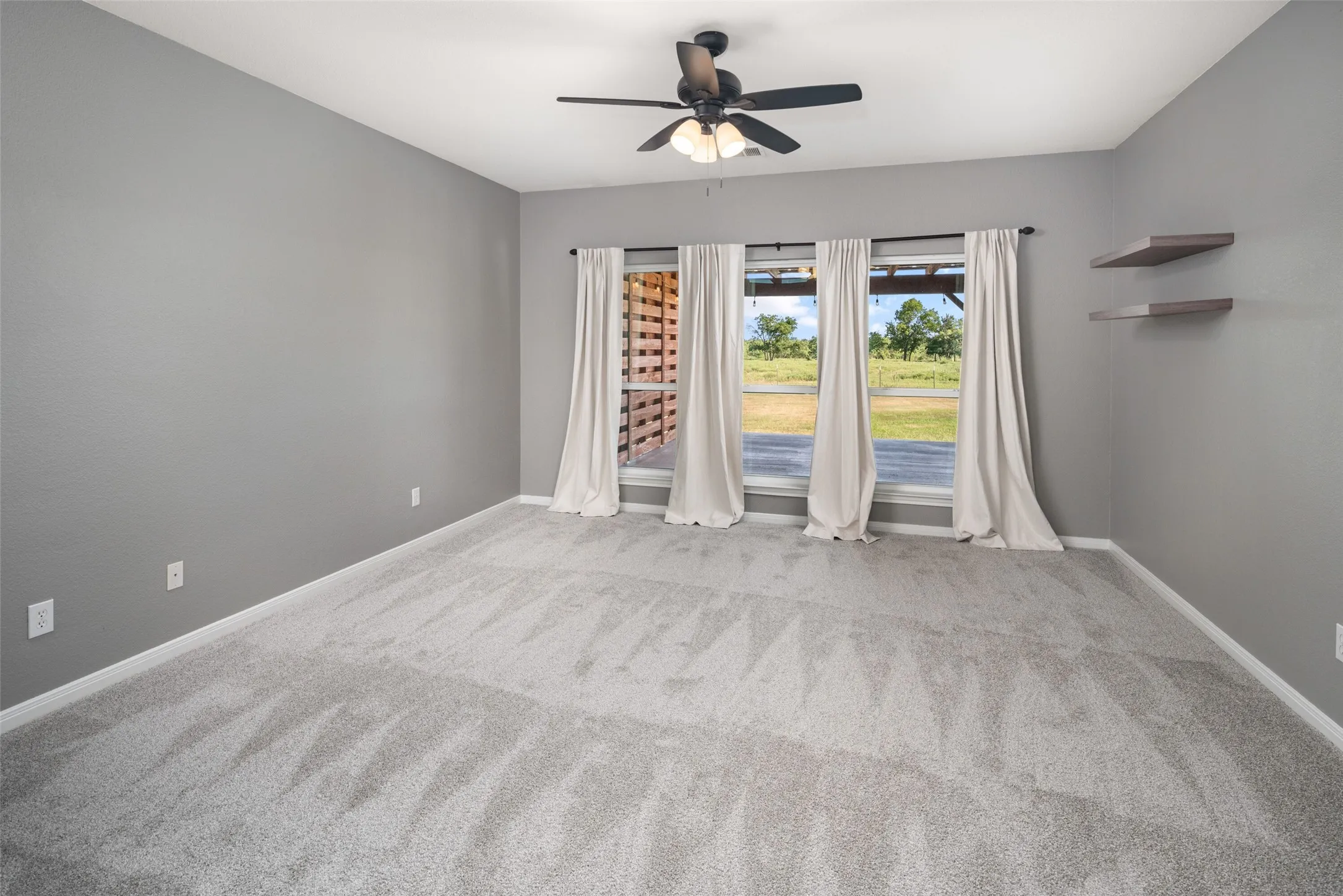 Spacious room featuring light gray carpet flooring and neutral gray walls