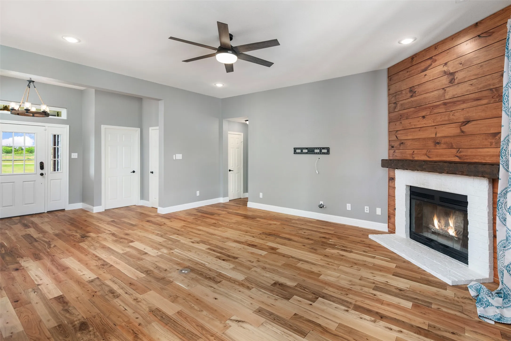 Spacious living area featuring wood-finish flooring, a ceiling fan, and recessed lighting