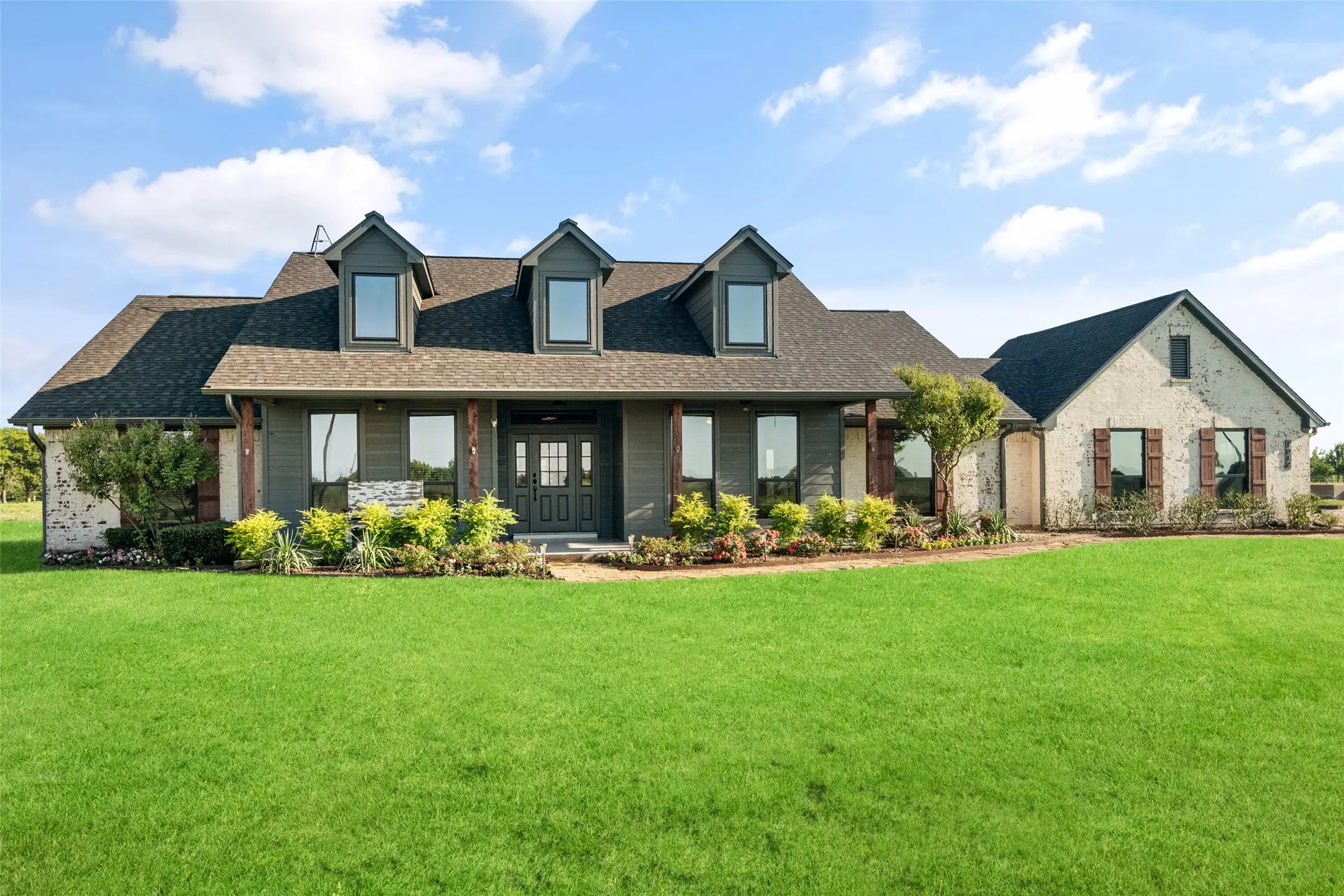 Expansive front lawn with a stone and siding exterior