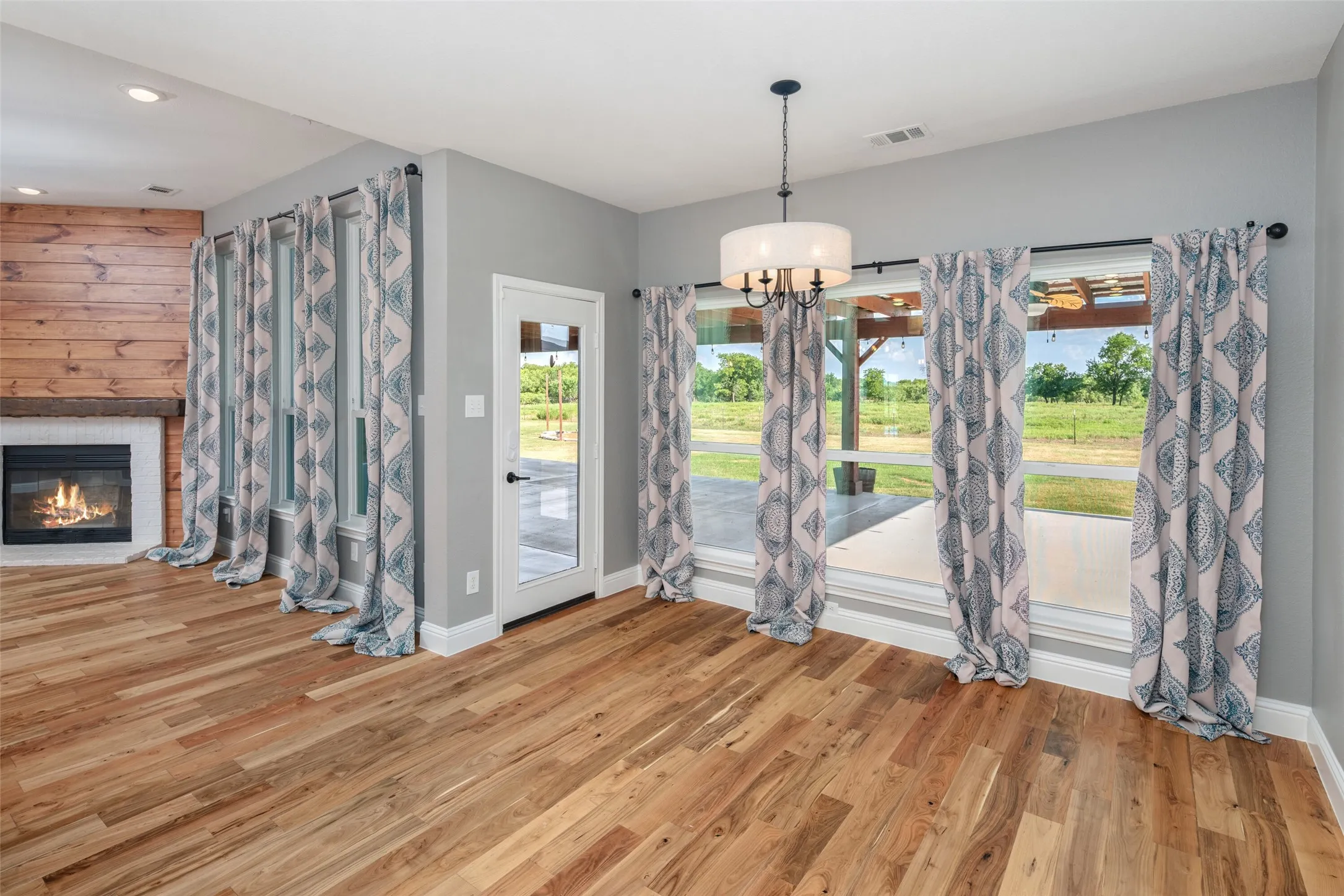 Spacious interior featuring wood-finish flooring, a contemporary fireplace with a wood mantle and shiplap accent wall, and multiple large windows