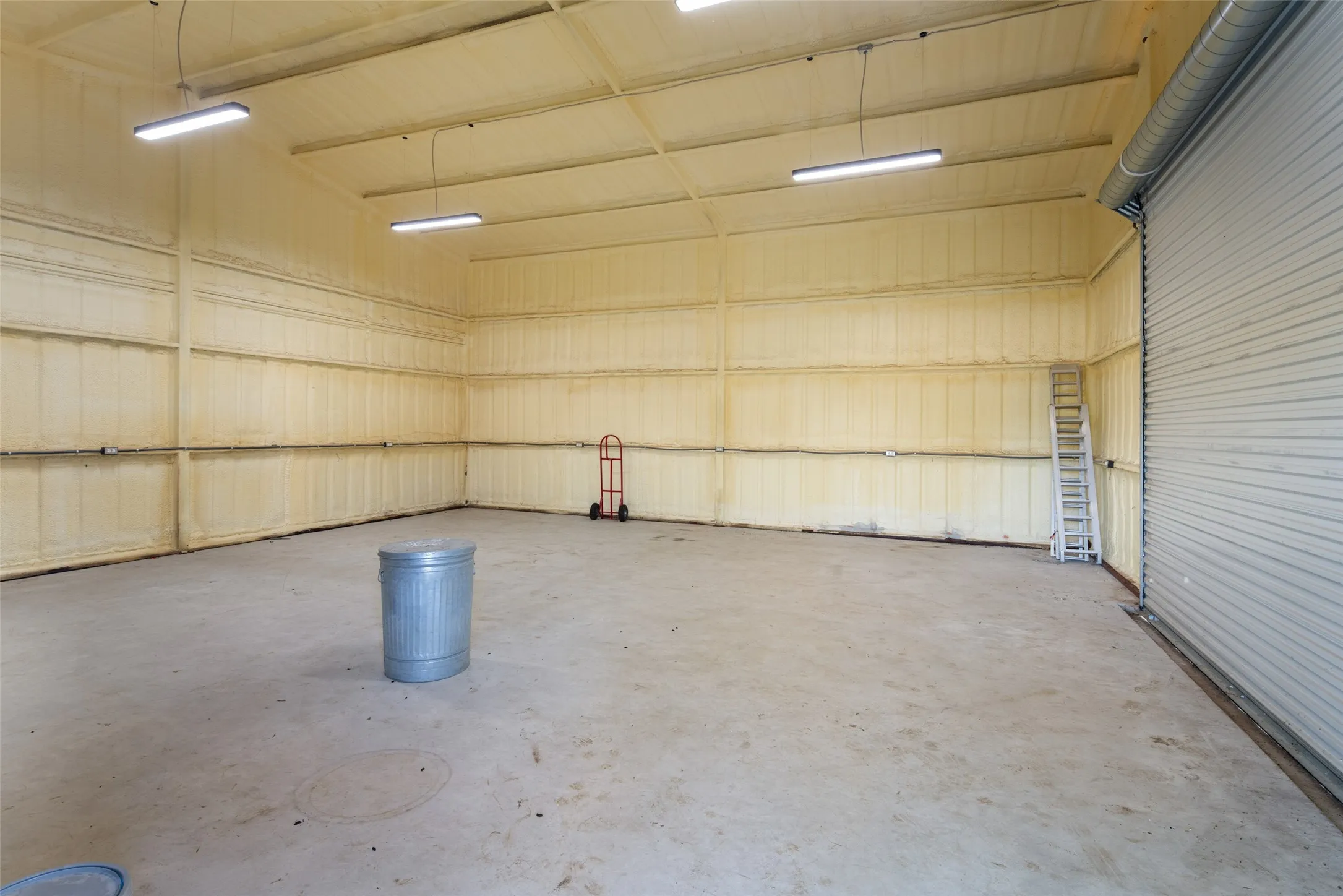 Spacious warehouse interior featuring a concrete floor, high ceilings, and spray foam insulation on all walls and ceiling