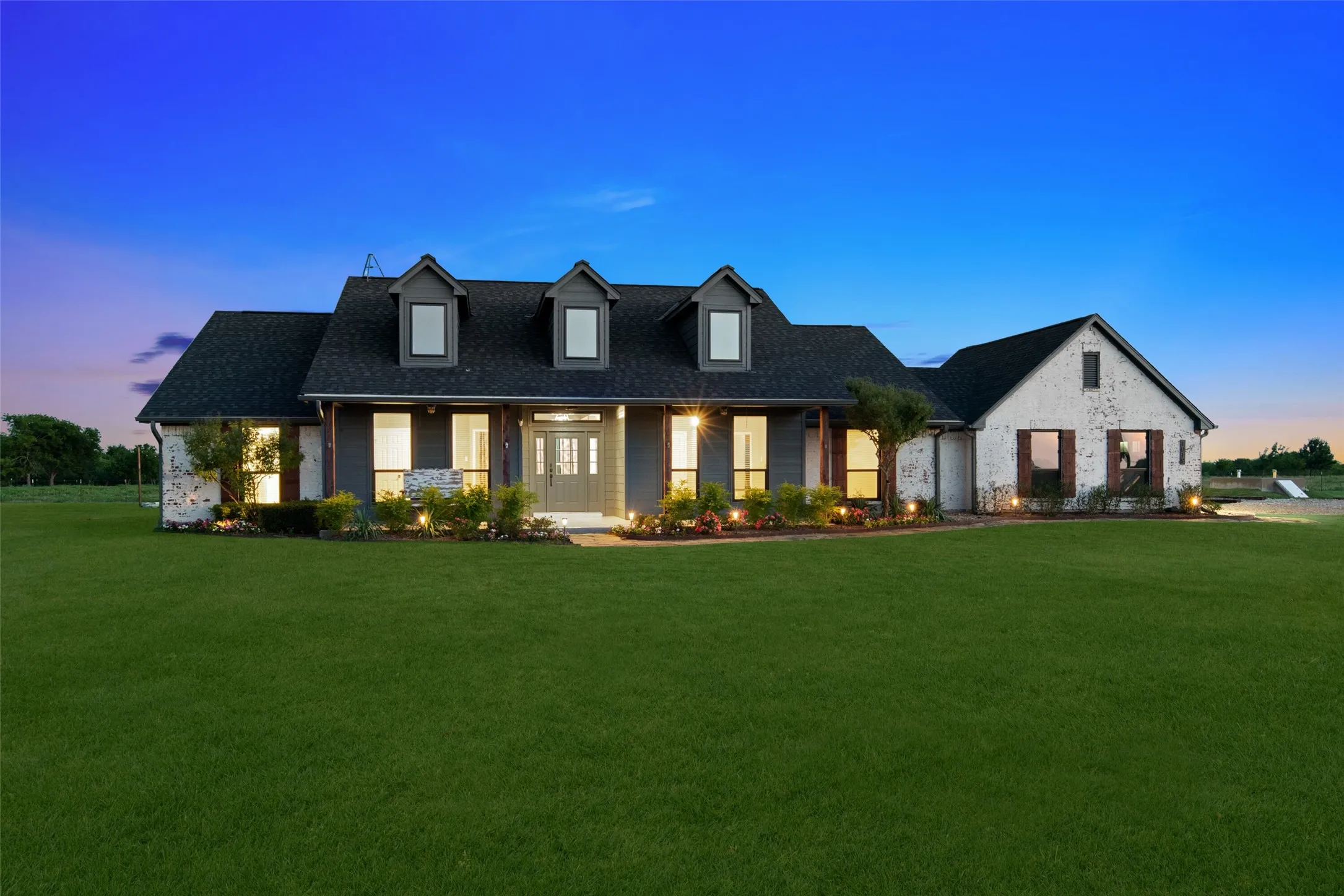 Modern farmhouse exterior featuring dark gray siding, white brick accents, and a dark shingle roof