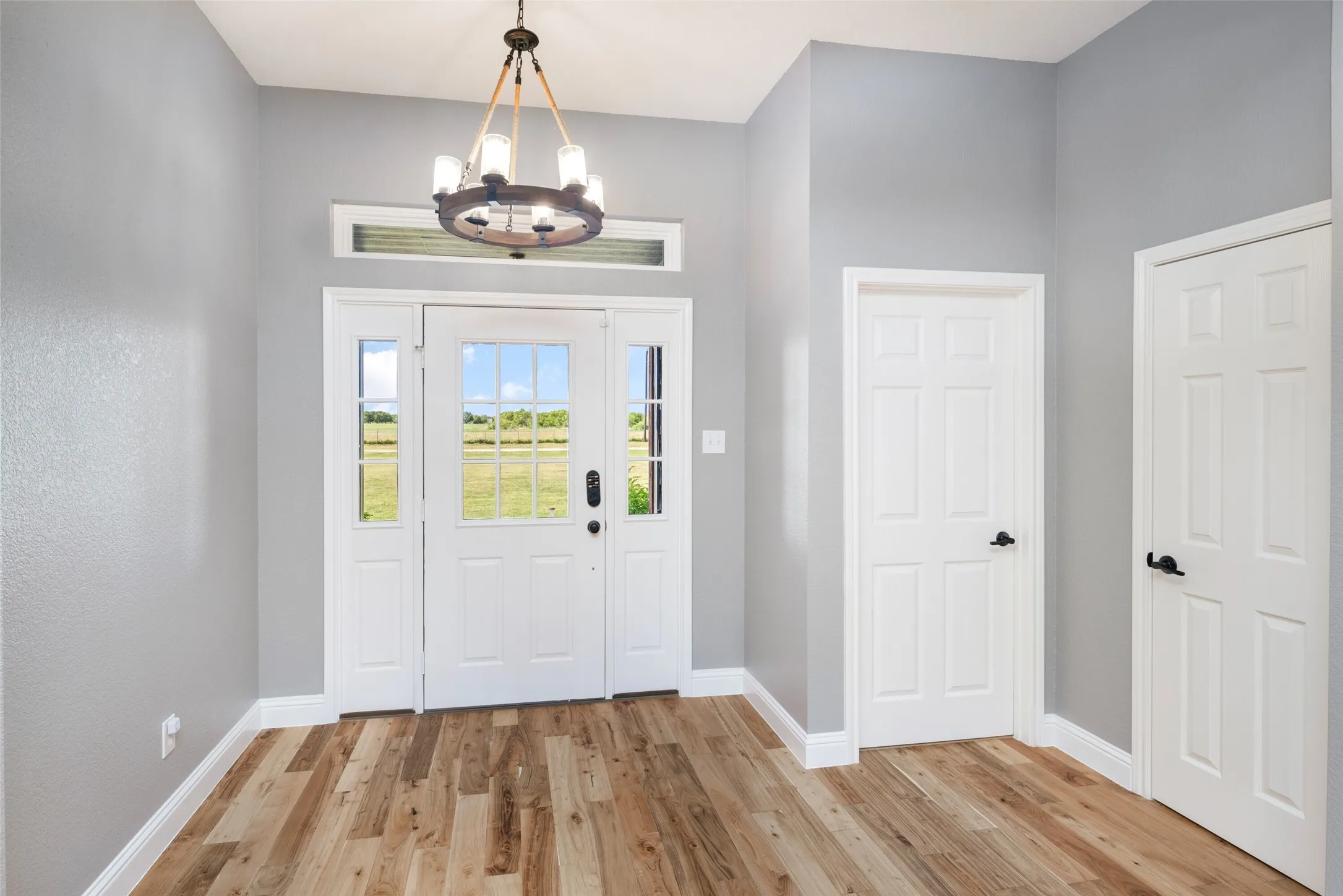 Foyer featuring a wood-finish flooring, white paneled doors, and a decorative chandelier
