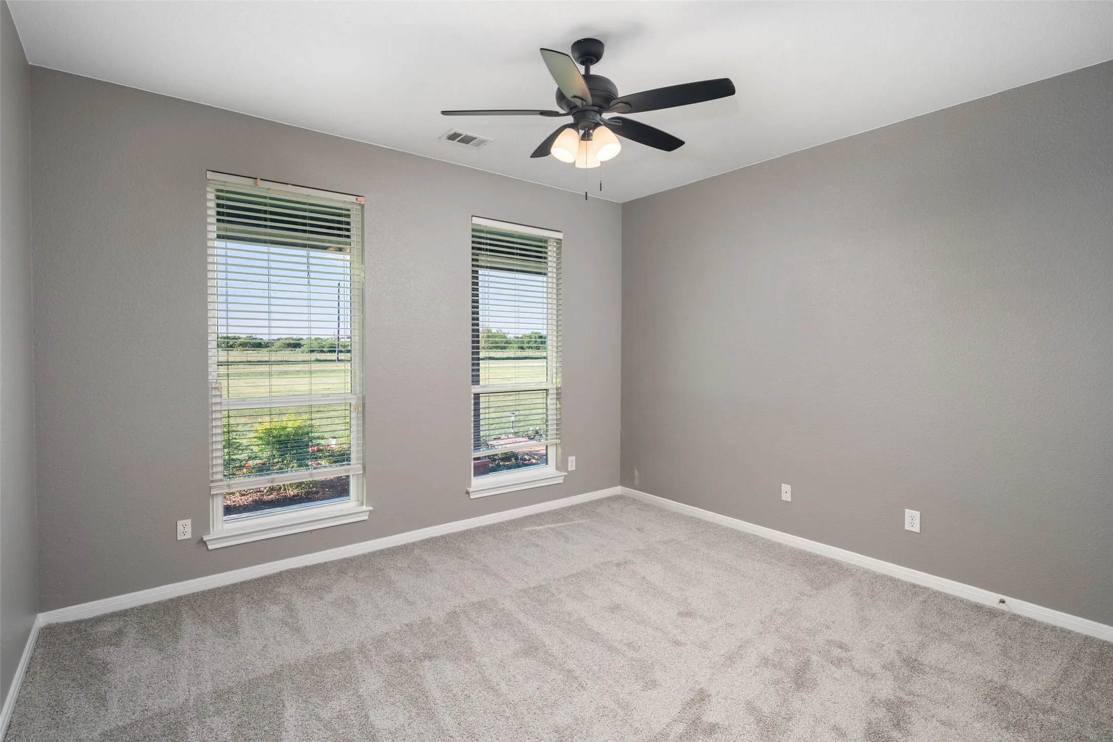 Spacious room featuring neutral grey wall paint and light grey carpeting
