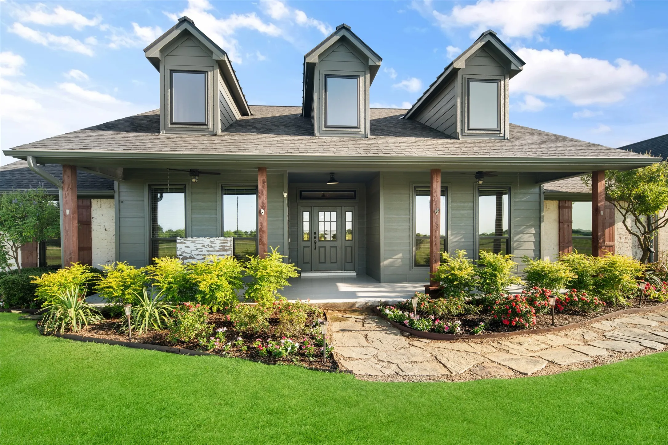 Contemporary home with dormer windows, a covered front porch, and a stone walkway