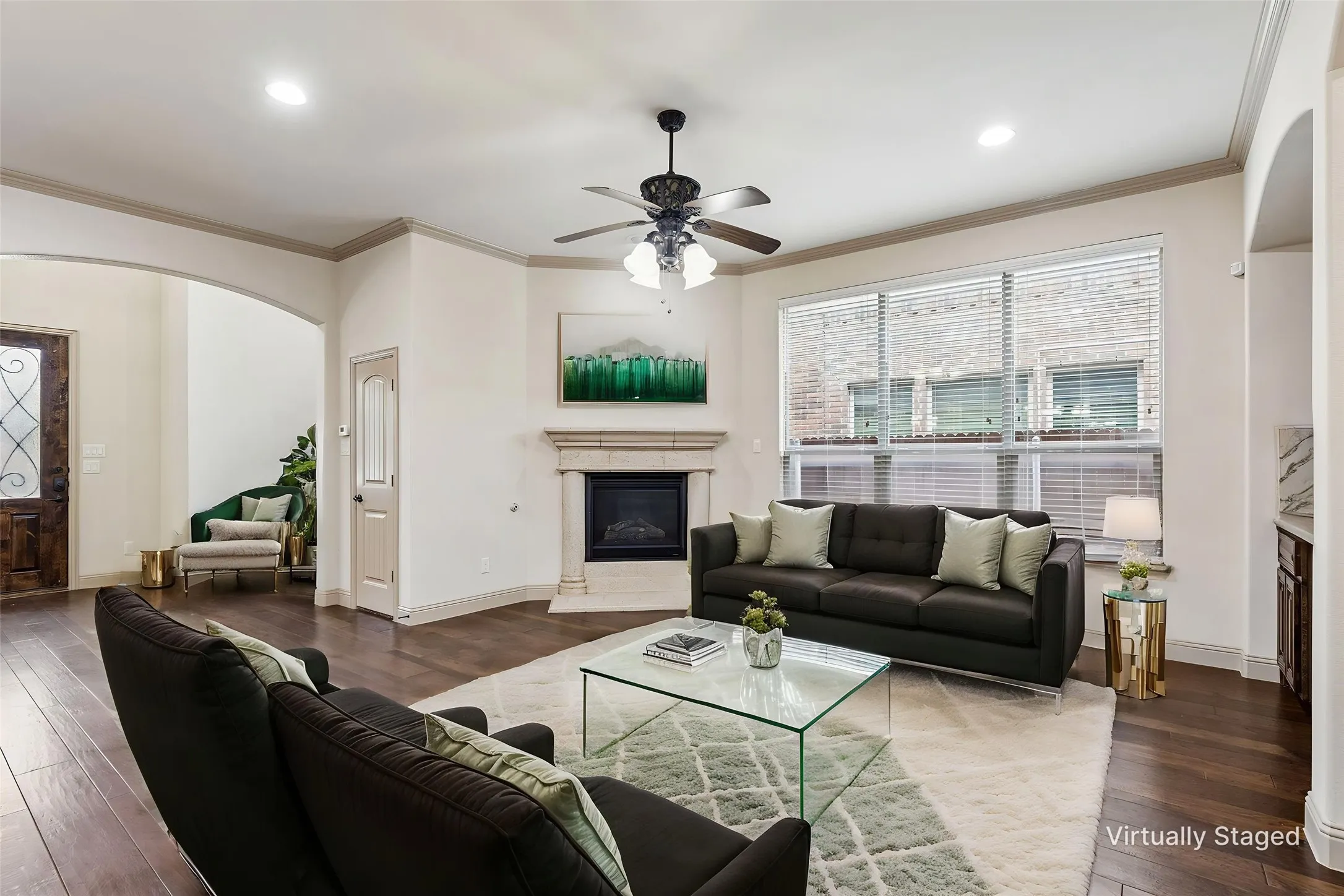 Spacious living area featuring wood-finish flooring, a corner fireplace with a stone surround, and multiple windows