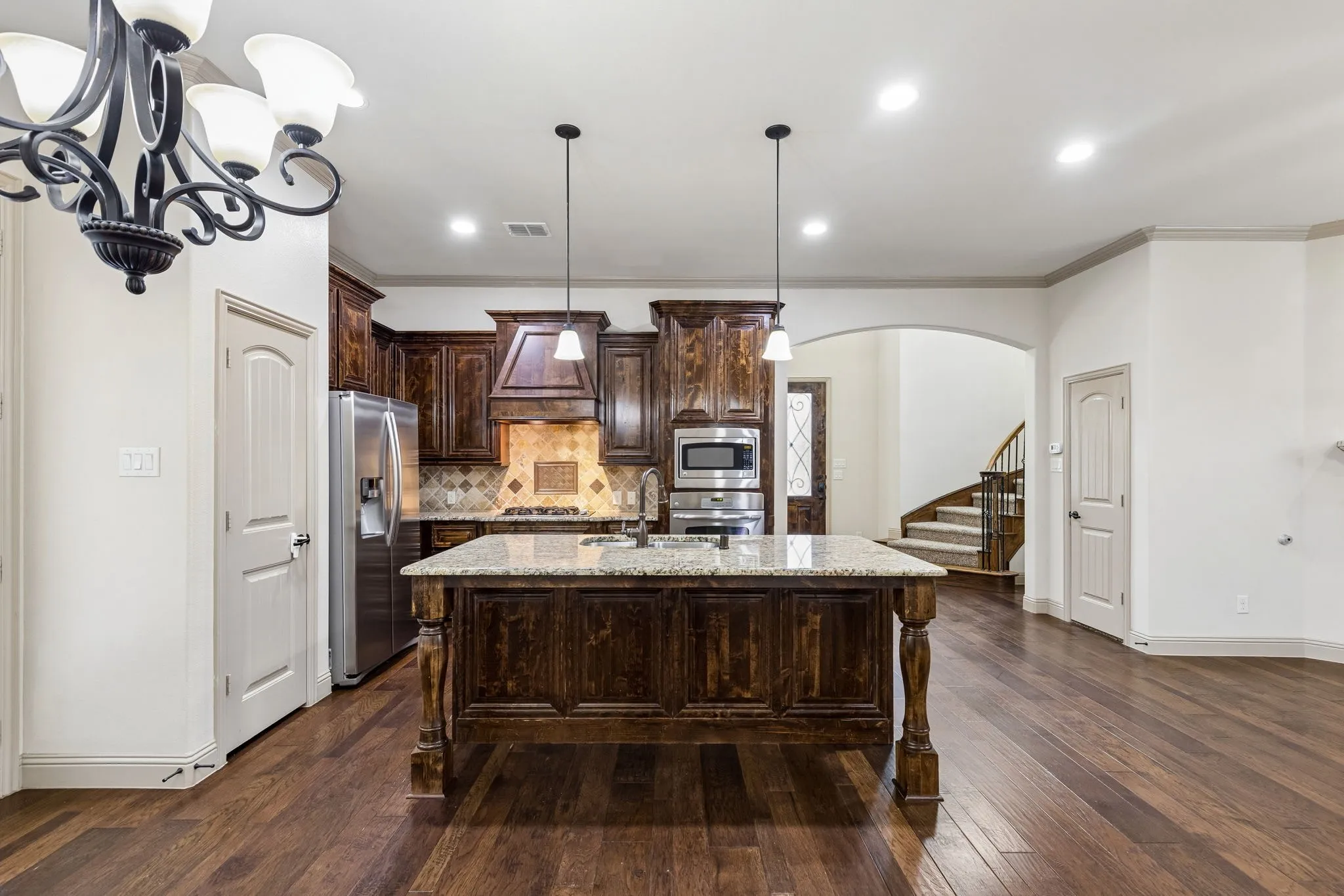 Kitchen featuring a central island with a stone countertop, dark wood cabinetry, stainless steel appliances, and wood-finish flooring