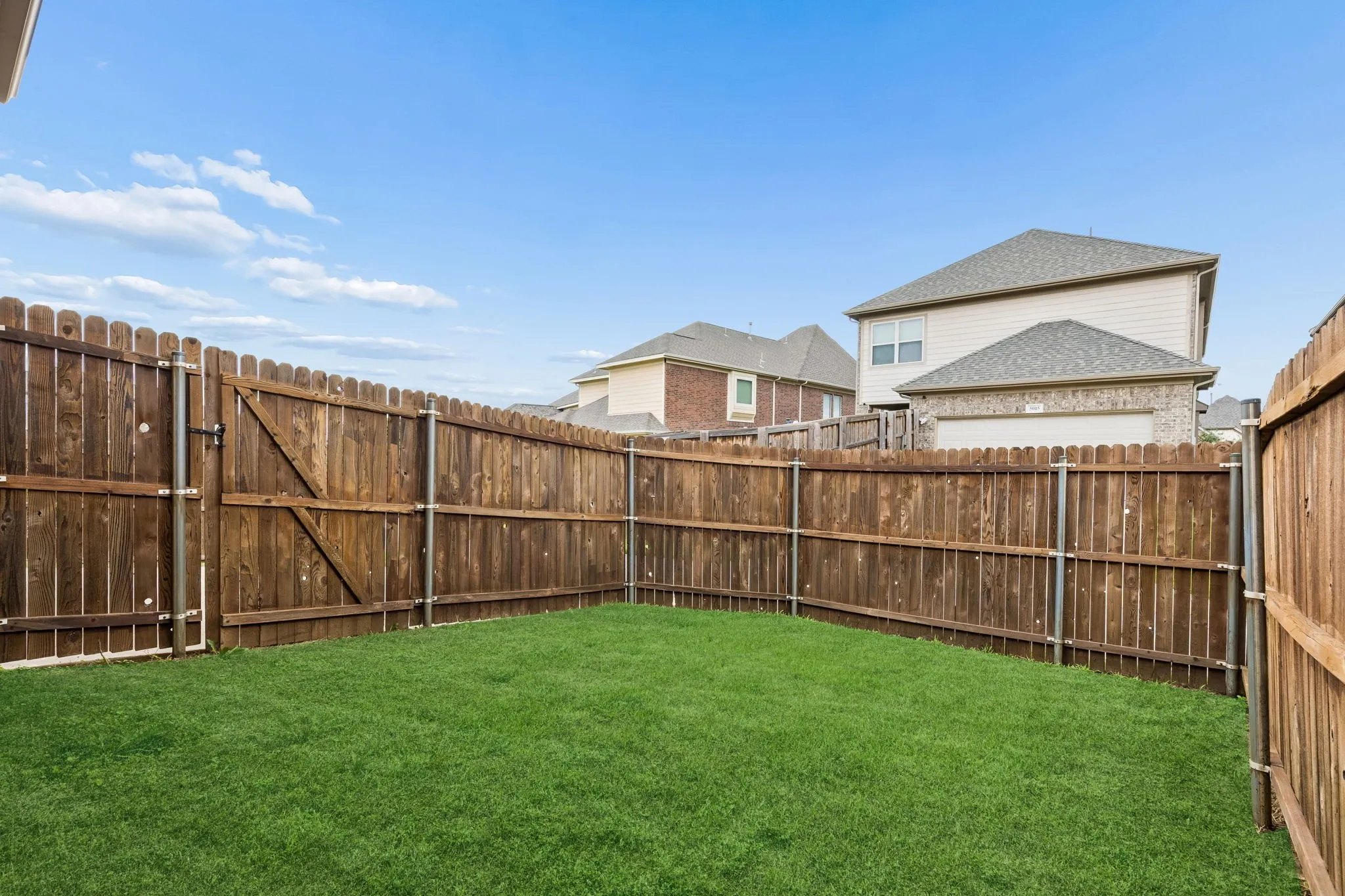 Private backyard featuring a well-maintained lawn and perimeter wood fencing with a gate