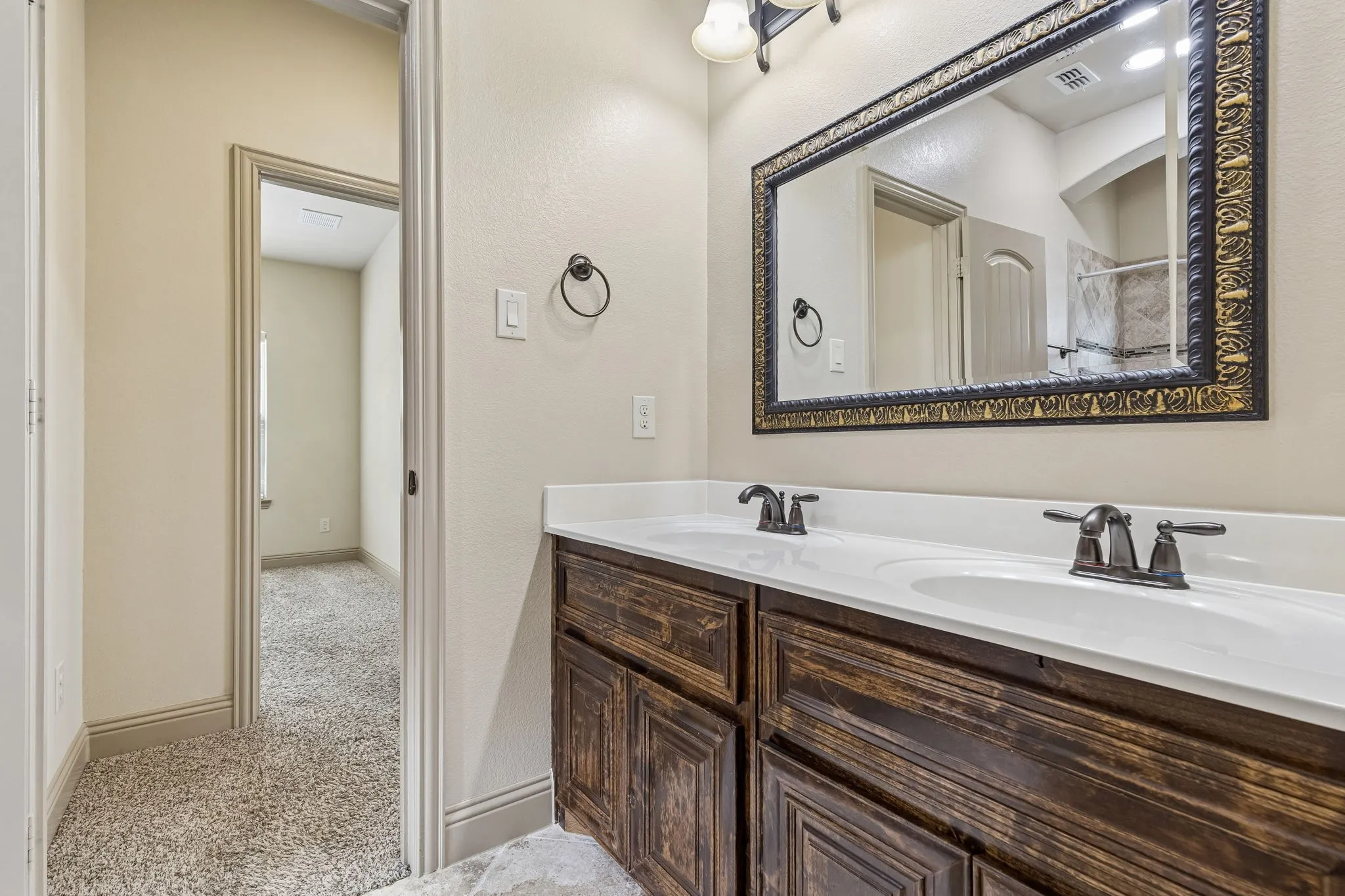 Double vanity jack and Jill featuring a white countertop with integrated sinks, dark wood-finish cabinetry, and oil-rubbed bronze hardware