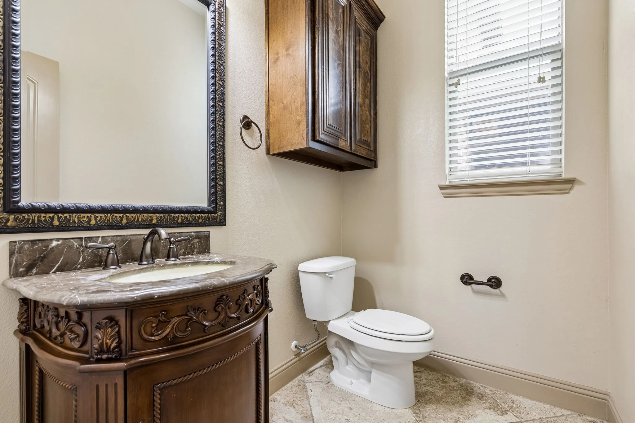 Powder  room featuring a carved wood vanity with a stone countertop and an undermount sink