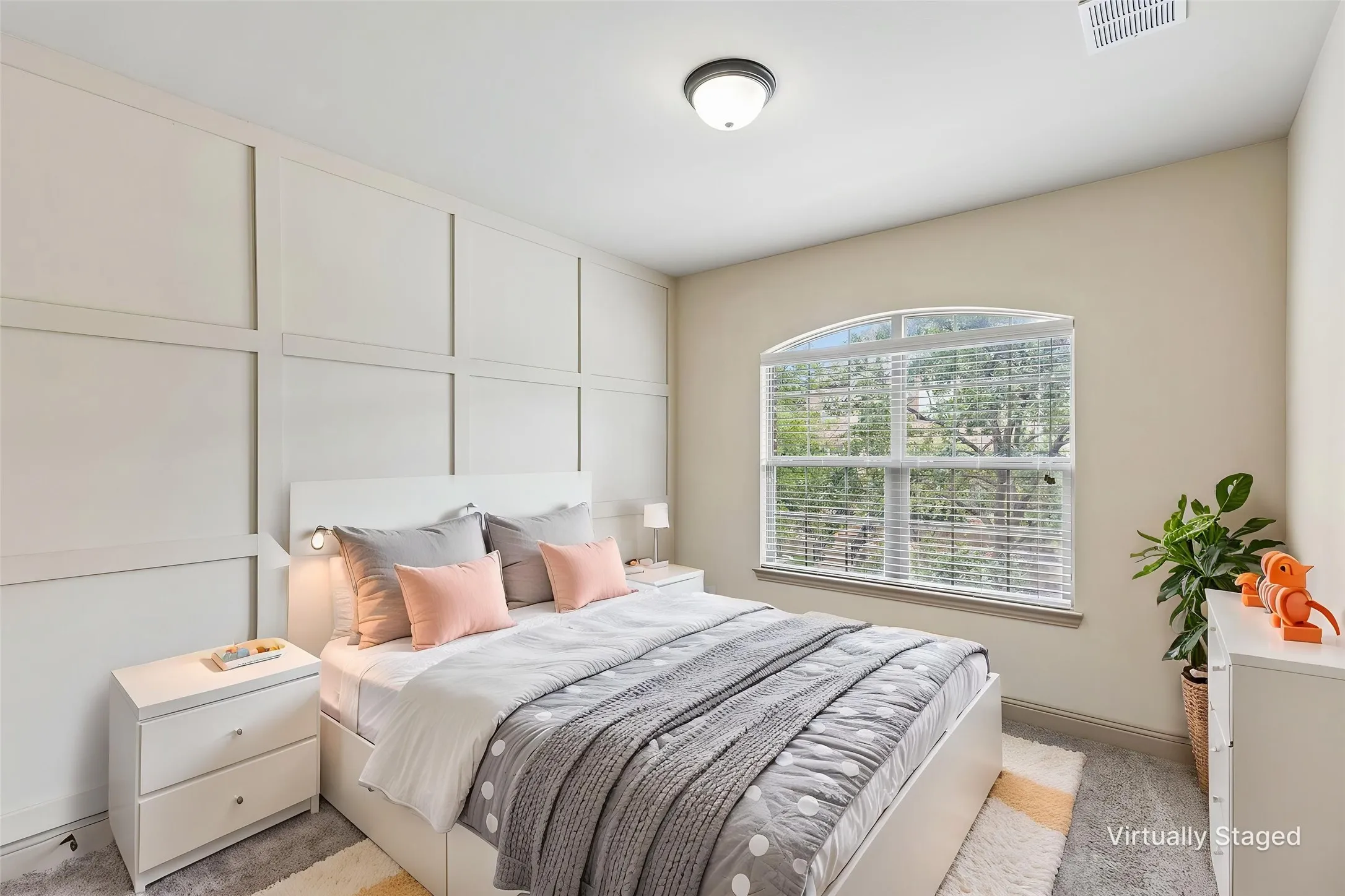 Bedroom featuring a decorative accent wall, arched window with horizontal blinds, overhead flush-mount lighting, and wall-to-wall carpeting