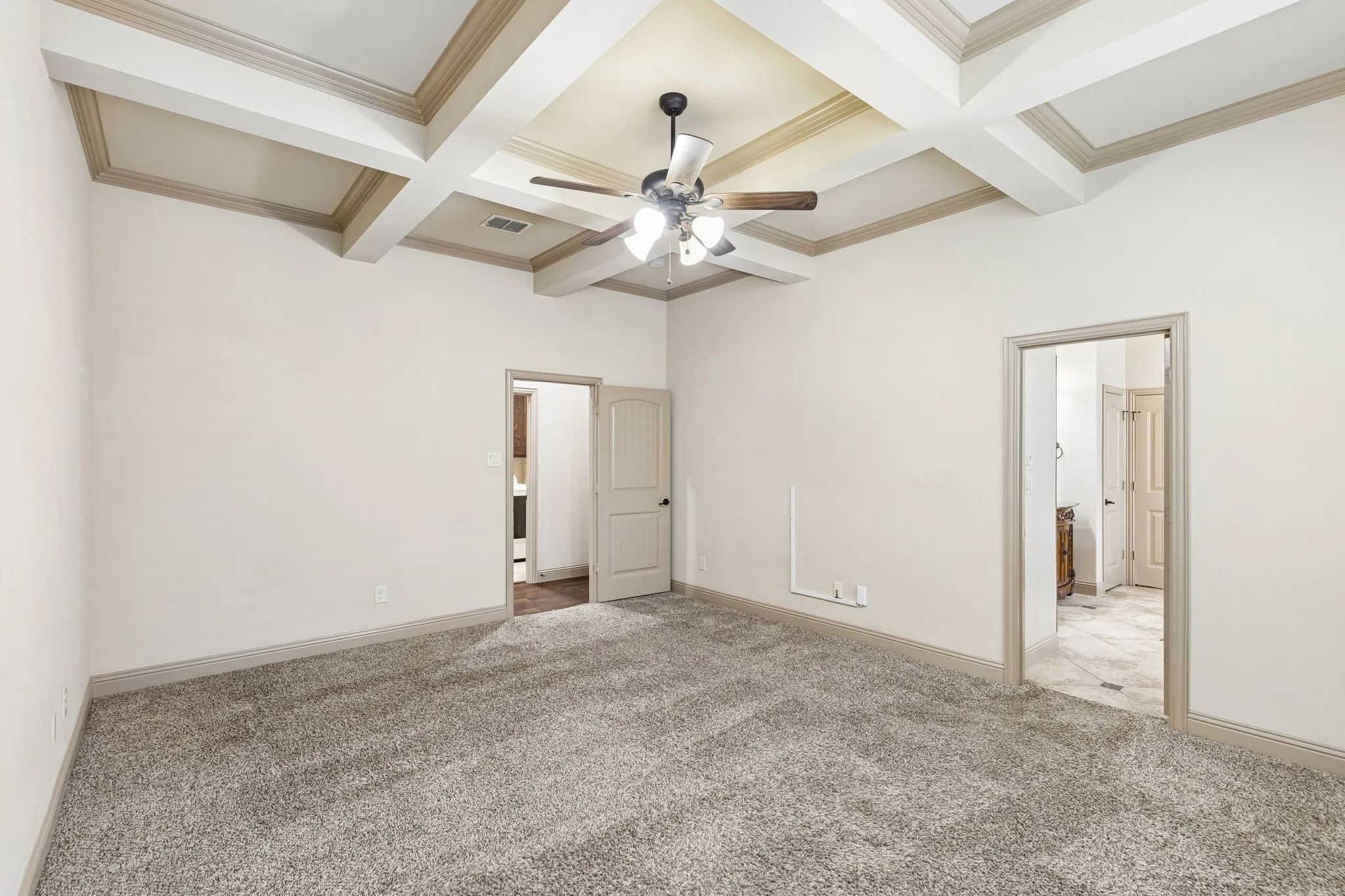 Spacious primary bed room featuring a tray ceiling with exposed beams, a ceiling fan with integrated lighting, and a large window with blinds