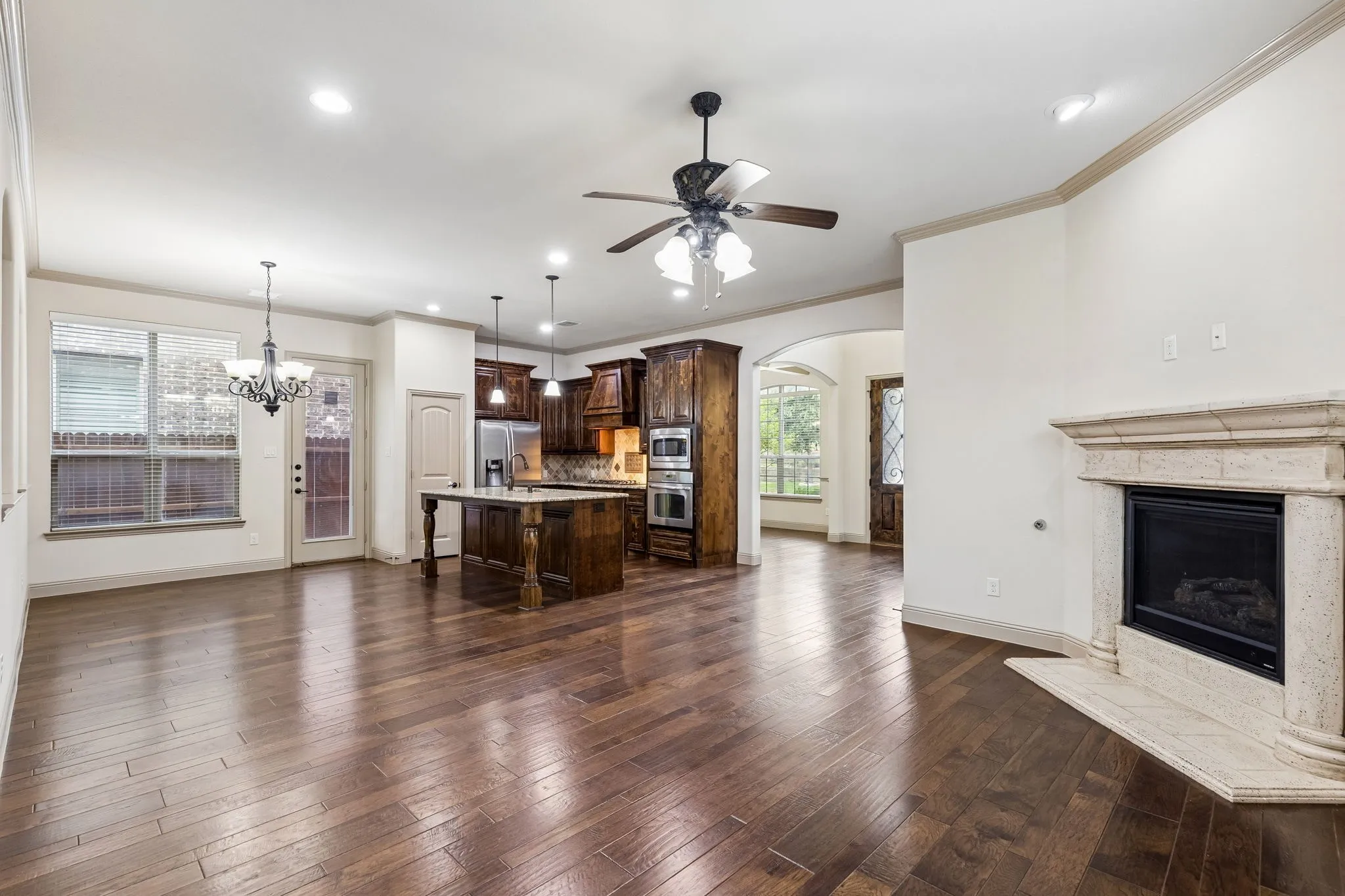 Spacious living area featuring wood-finish flooring, a decorative fireplace with a substantial mantel, and recessed lighting