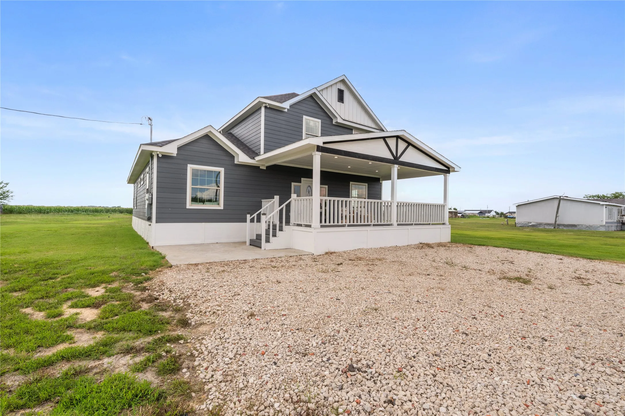 Two-story residence featuring dark gray siding, white trim, and a covered porch with a white railing