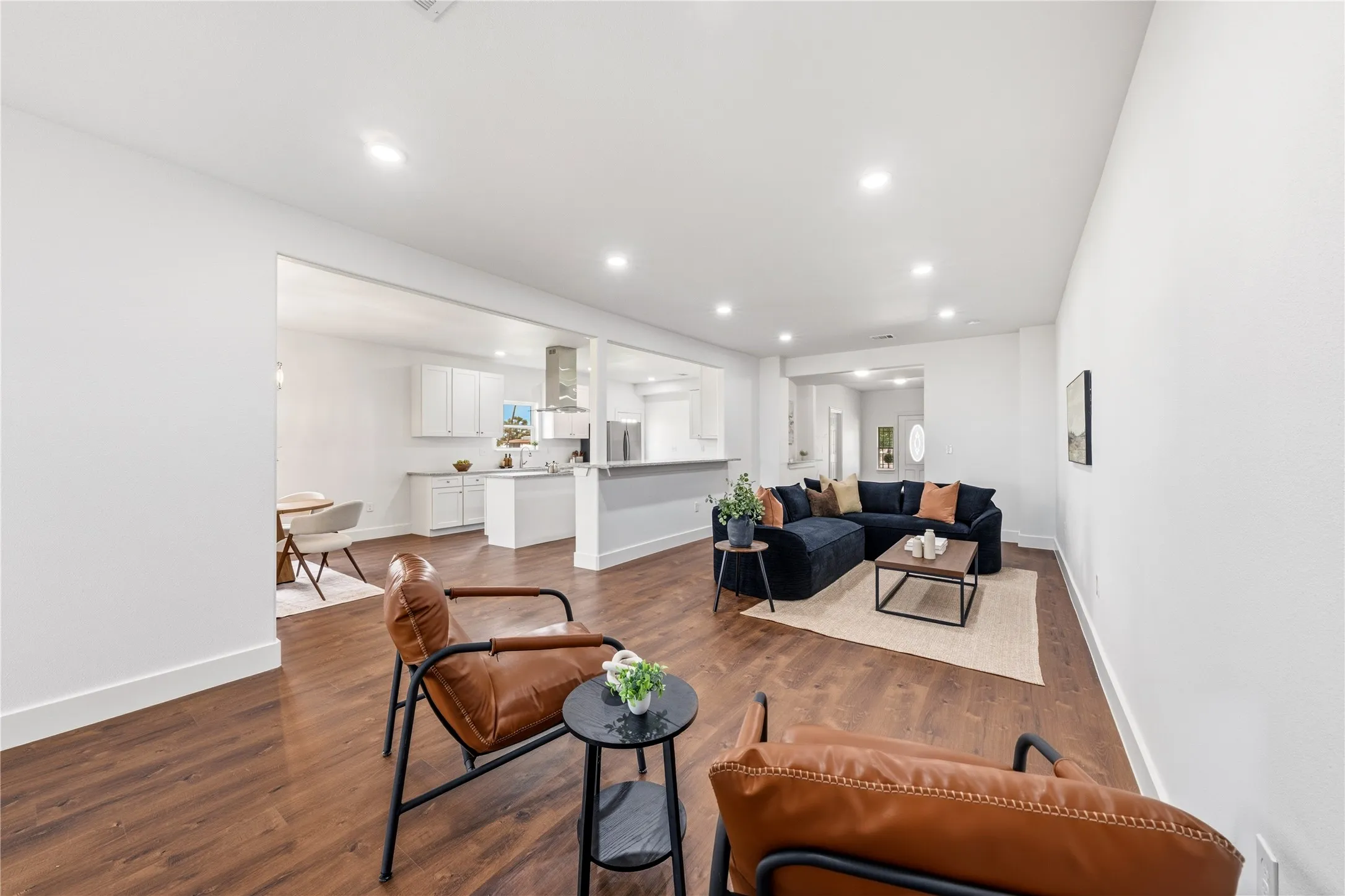 Open-concept interior featuring wood-finish flooring, recessed lighting, white walls, and substantial baseboards