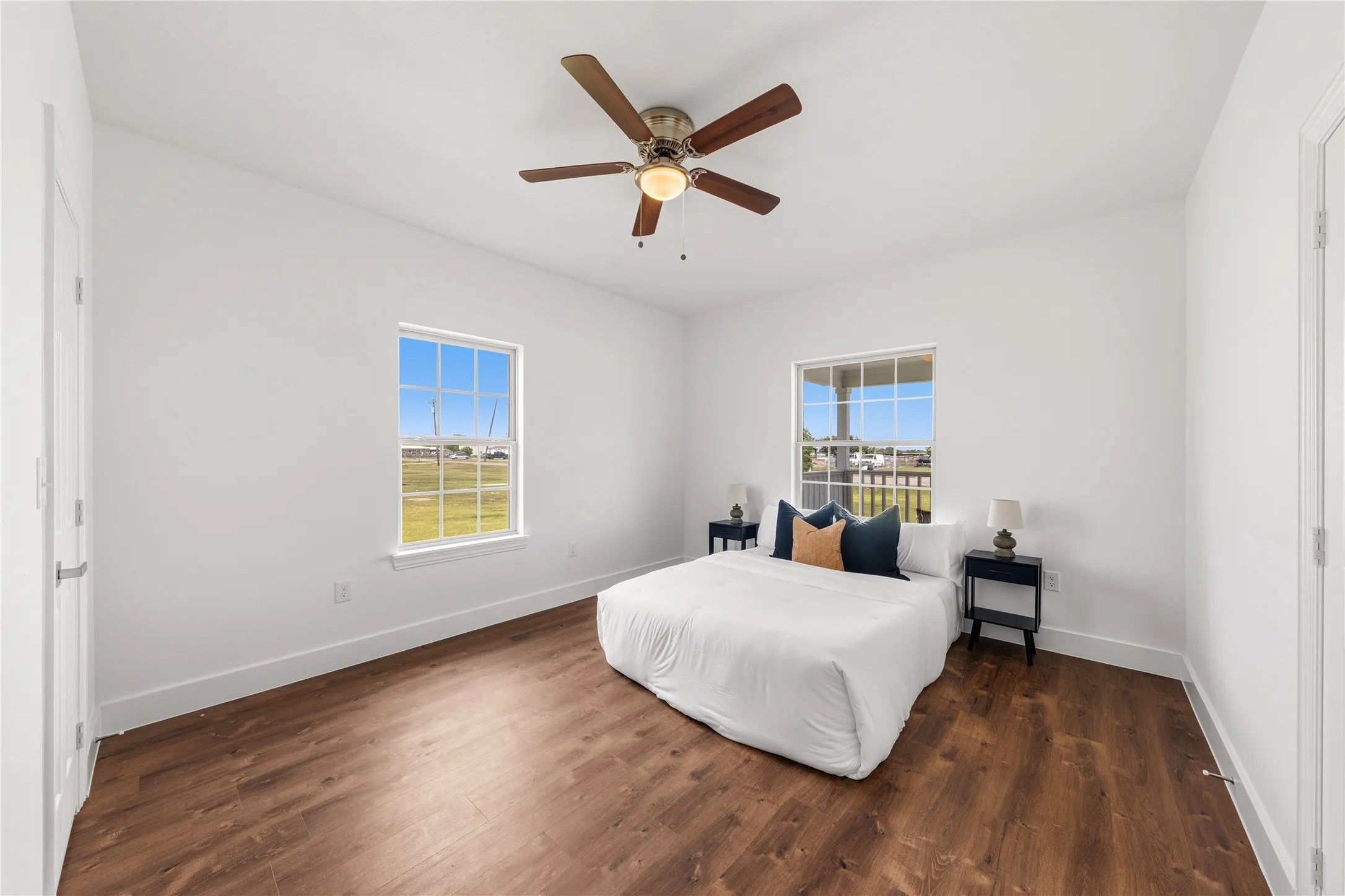 Bright room featuring wood-finish flooring, white walls, and a ceiling fan with integrated lighting