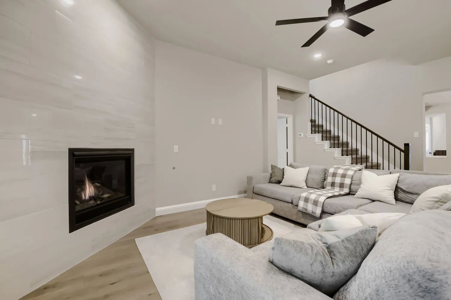 Living area featuring a modern fireplace with a white tile surround, and light wood-finish flooring.