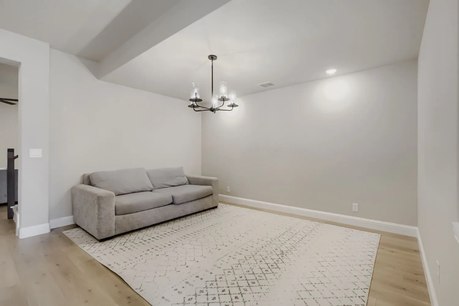 Spacious room featuring wood-finish flooring, a contemporary chandelier, recessed lighting, and crisp baseboards