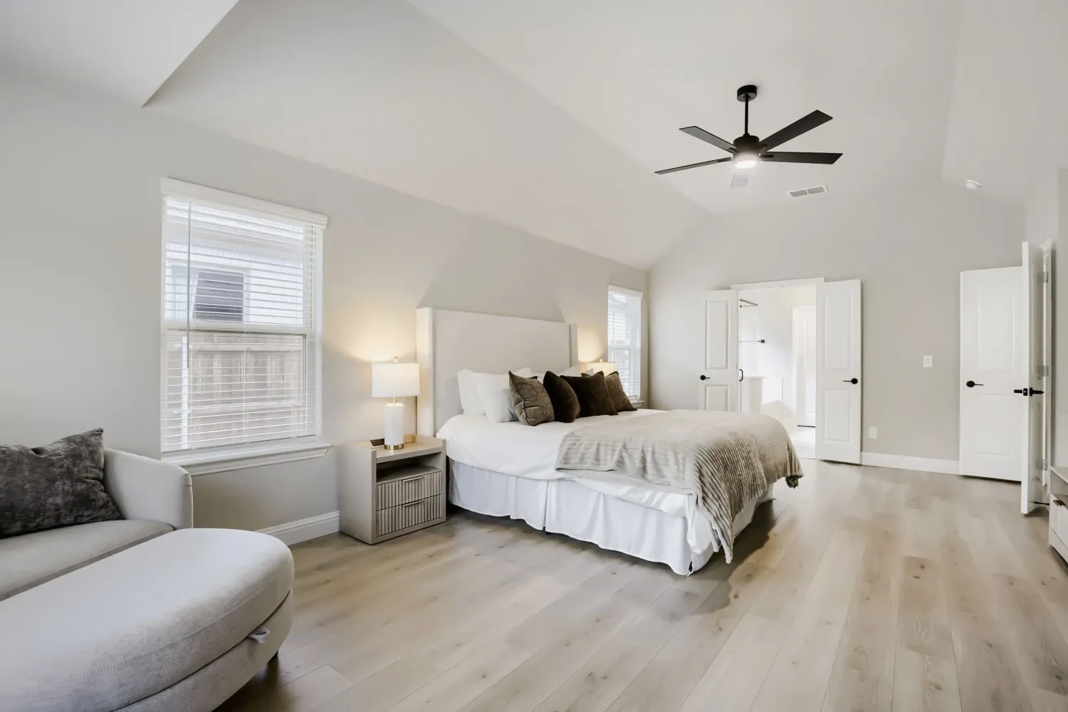 Spacious bedroom with vaulted ceilings, wood-finish flooring, and a contemporary ceiling fan