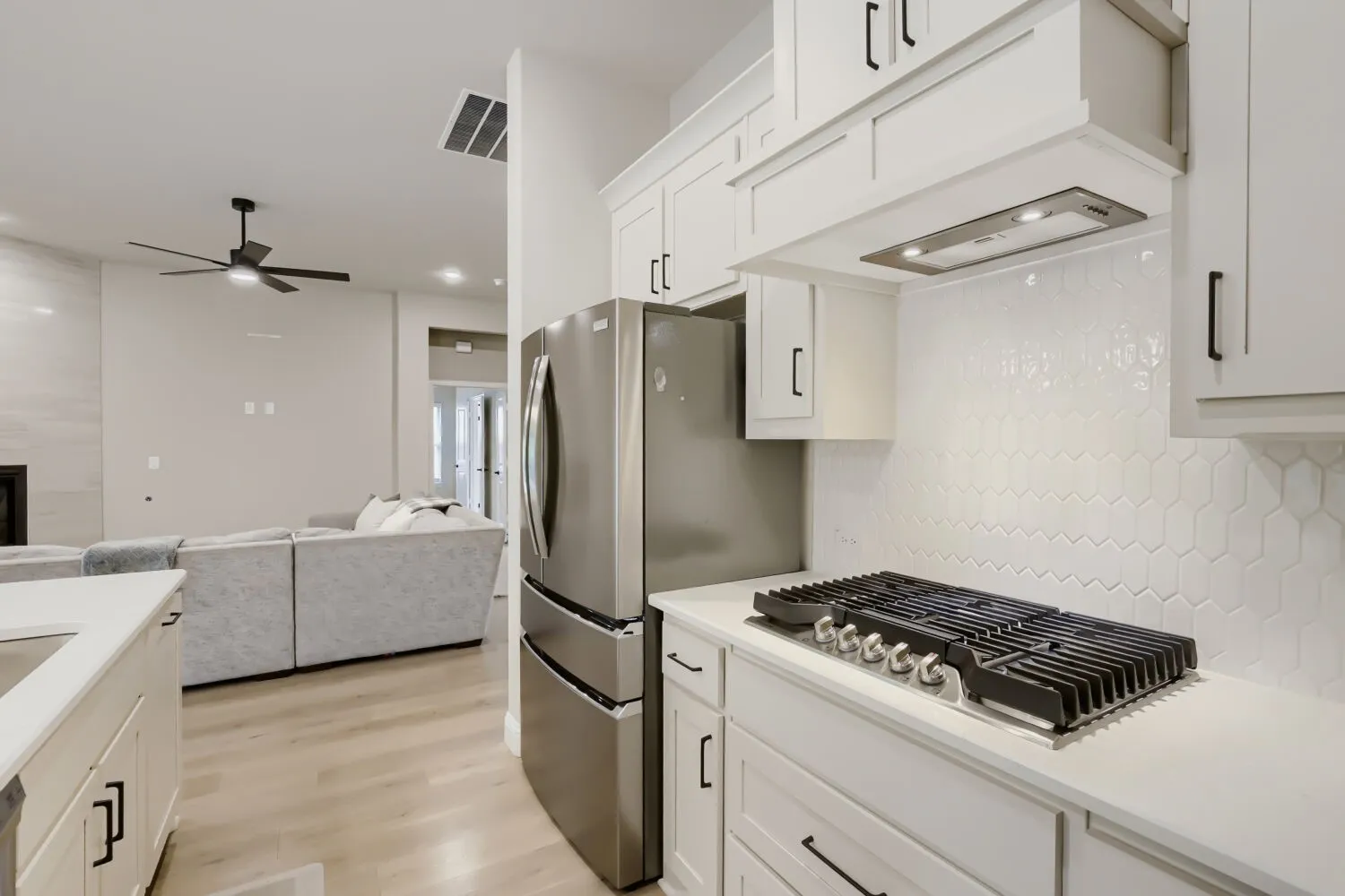 Kitchen featuring white cabinetry, stainless steel appliances, a gas cooktop, and a textured white tile backsplash