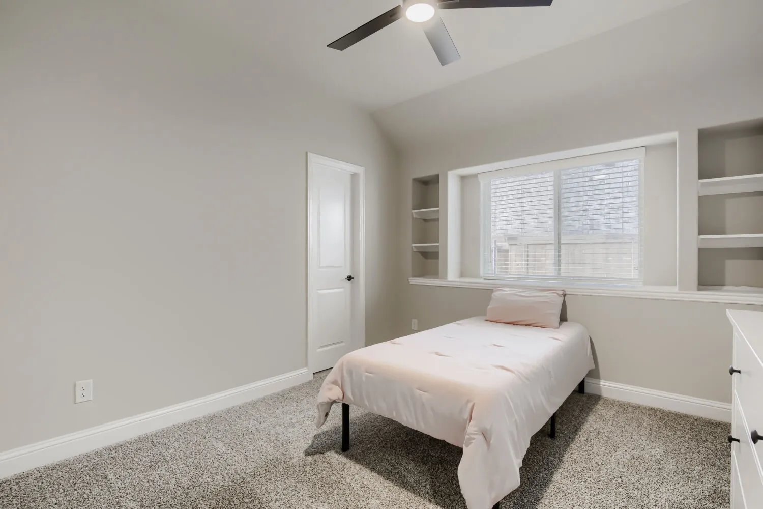 Carpeted room with a modern ceiling fan, a window featuring blinds, and integrated shelving units