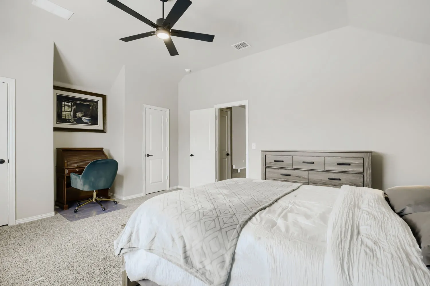 Carpeted bedroom with vaulted ceilings, a black ceiling fan, and white interior doors with black hardware