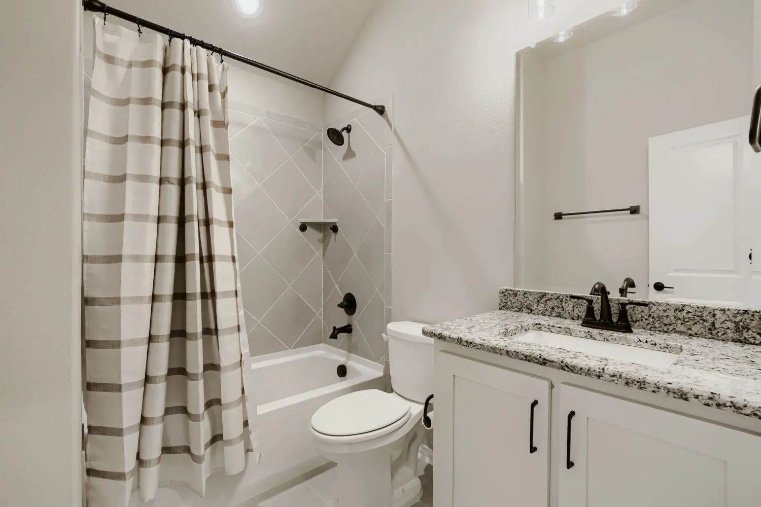 Bathroom featuring a white vanity with a granite countertop, integrated sink, and matte black fixtures